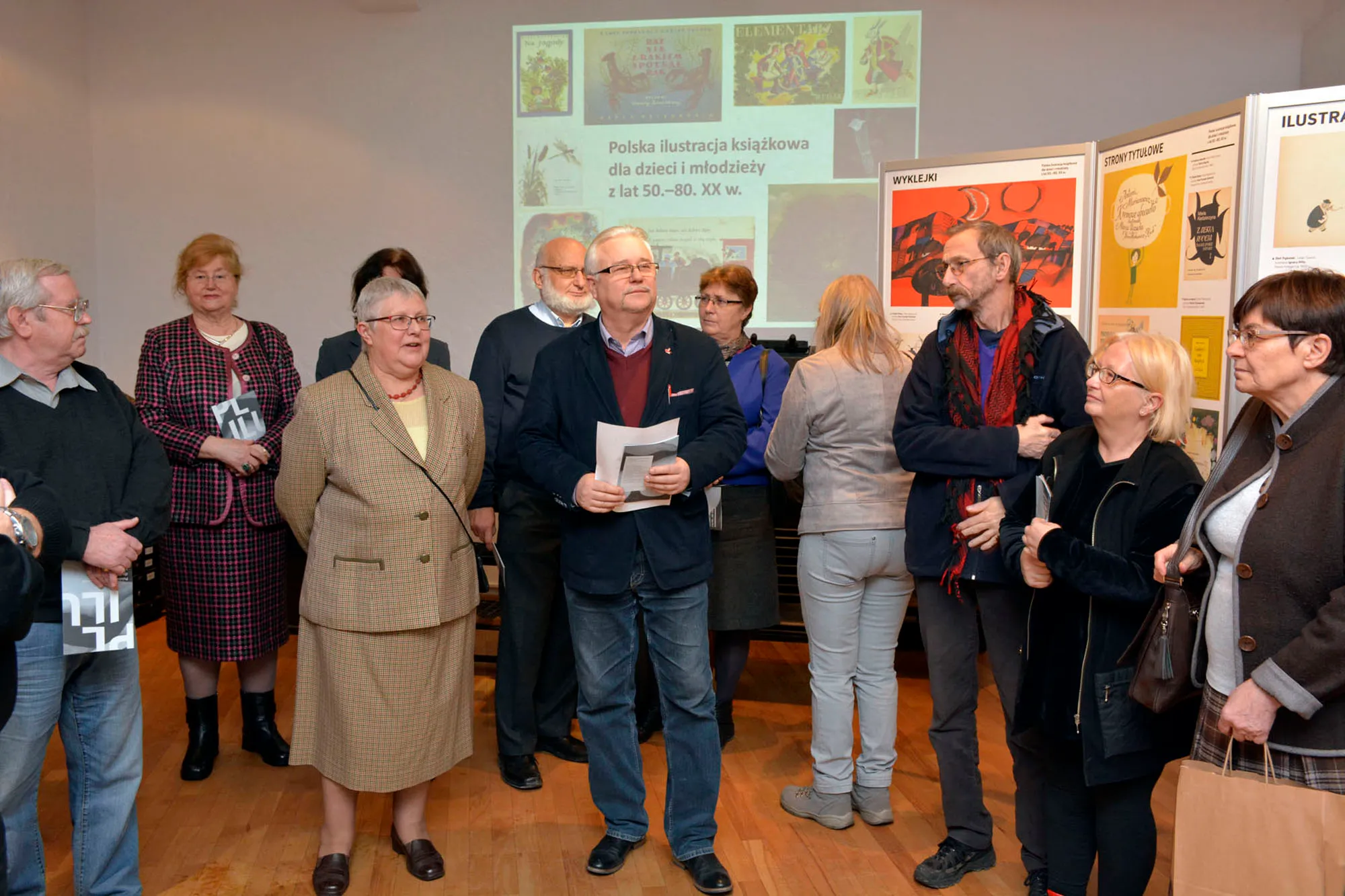 people standing in an exhibition space looking at artwork and posters on display