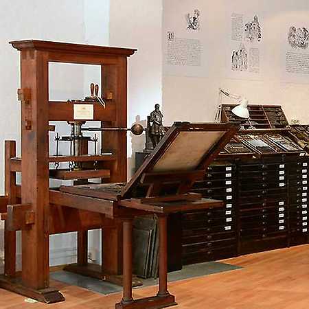 wooden printing press with a composing stand and type drawers in a museum exhibit