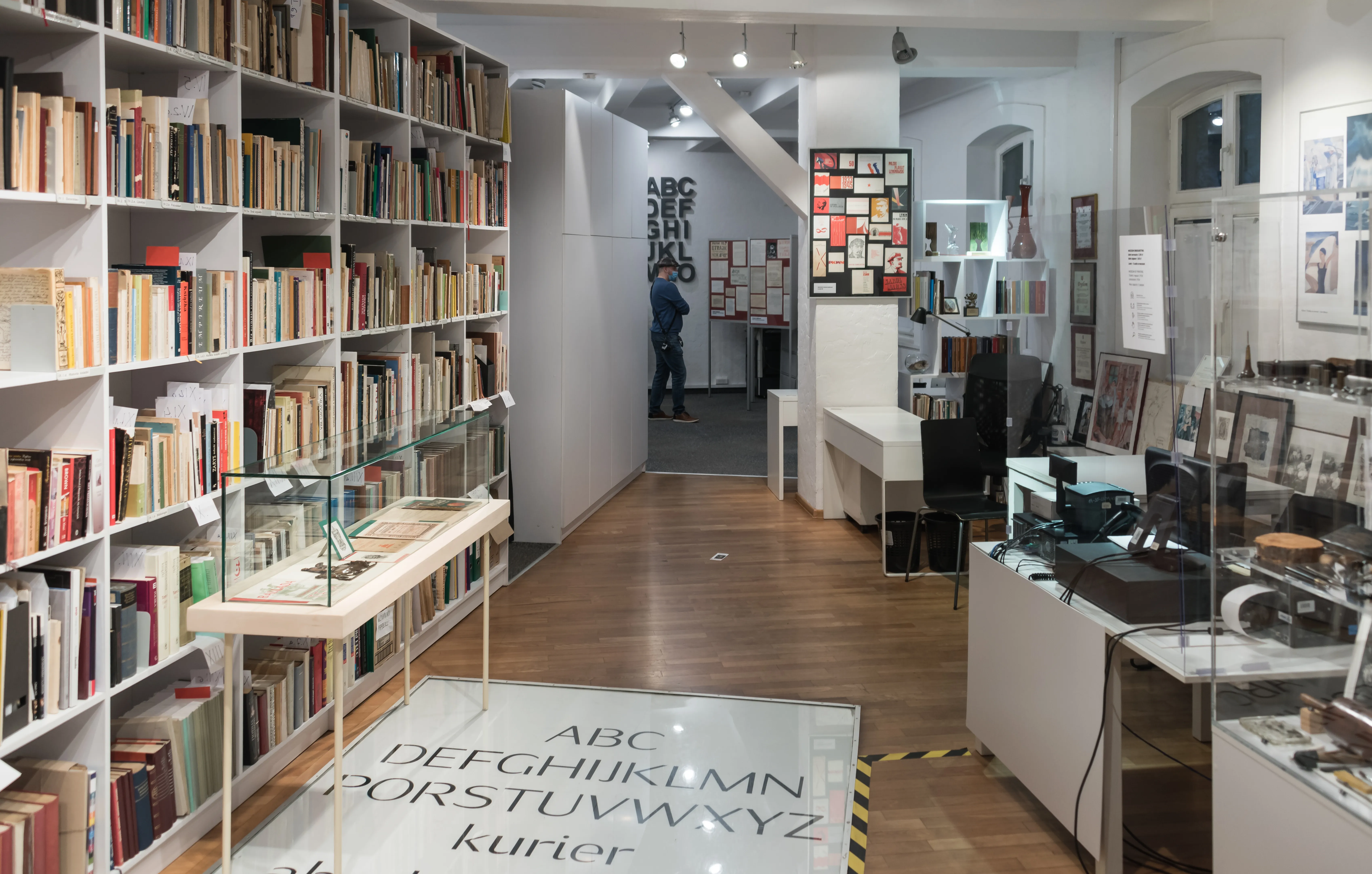 Interior of a museum with bookshelves, display cases, and a large alphabet mat on the floor