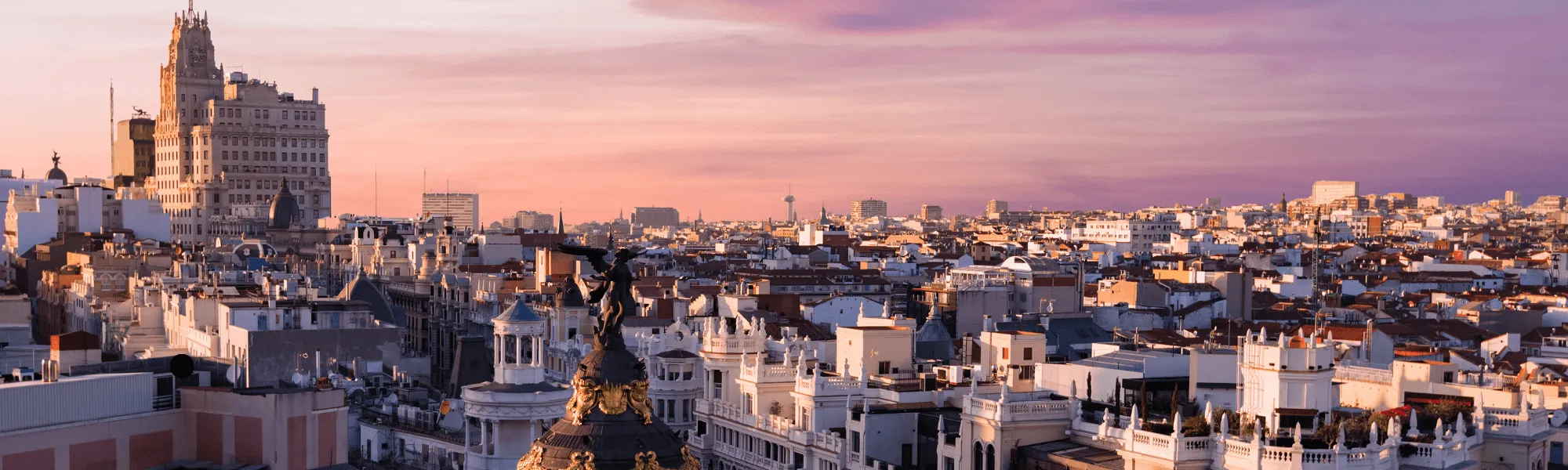 Panoramisch stadsgezicht van Madrid bij zonsondergang met talloze gebouwen en een prominente toren in de verte