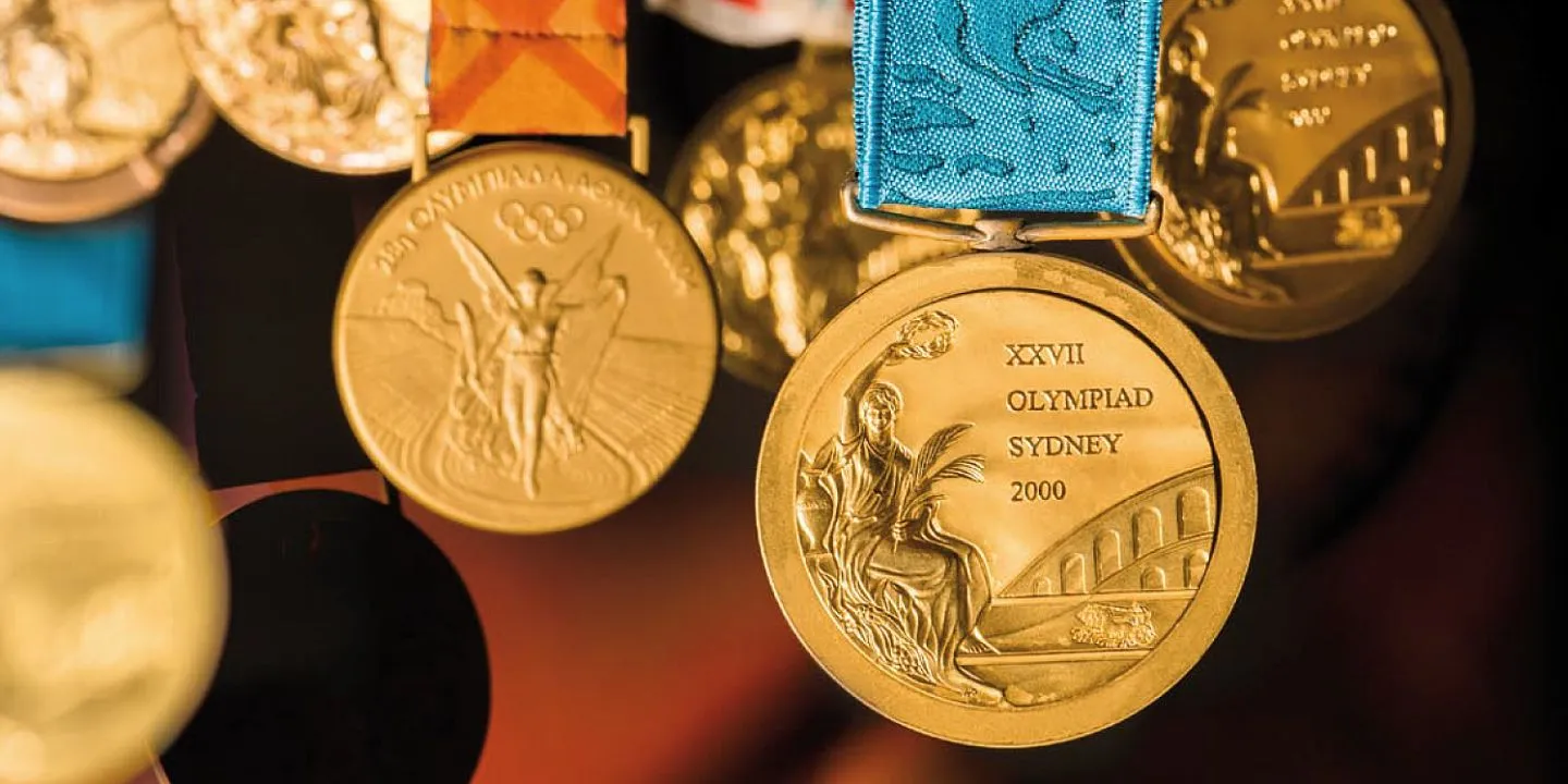 Close-up of Olympic medals, including a gold medal from the 2000 Sydney Olympics with a blue ribbon.