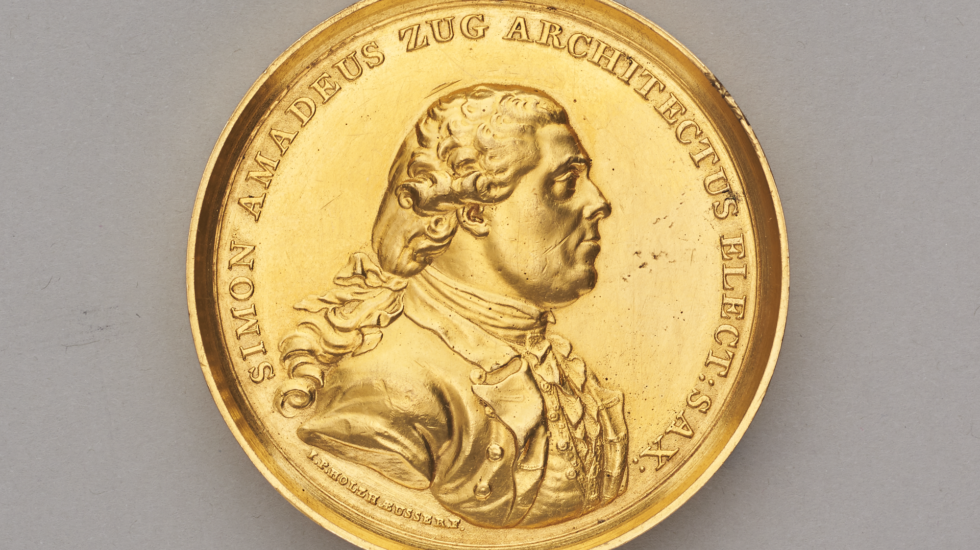 gouden medaillon met profiel van een man en Latijnse tekst