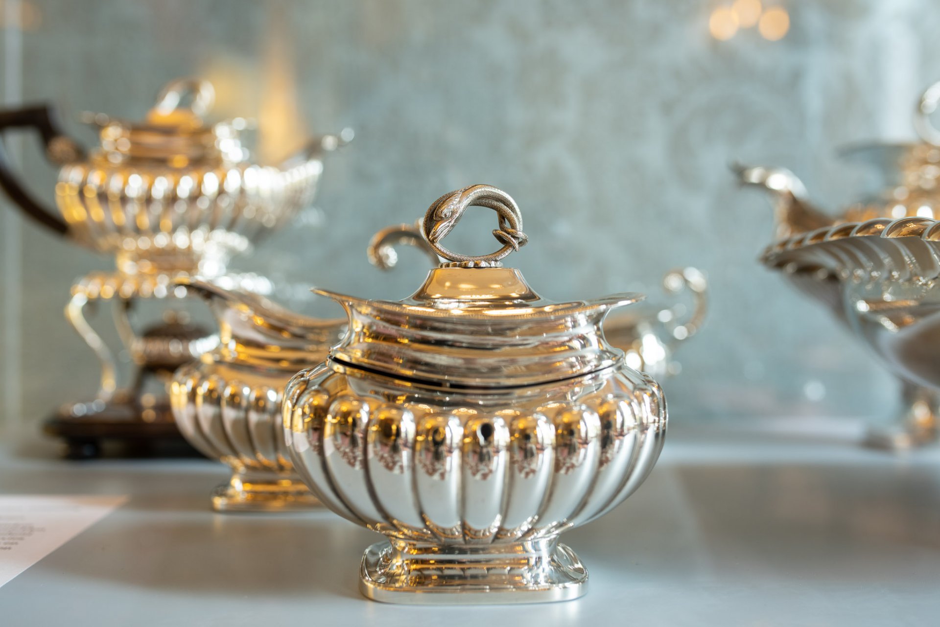 Ornate silver containers with intricate detailing displayed in a museum setting