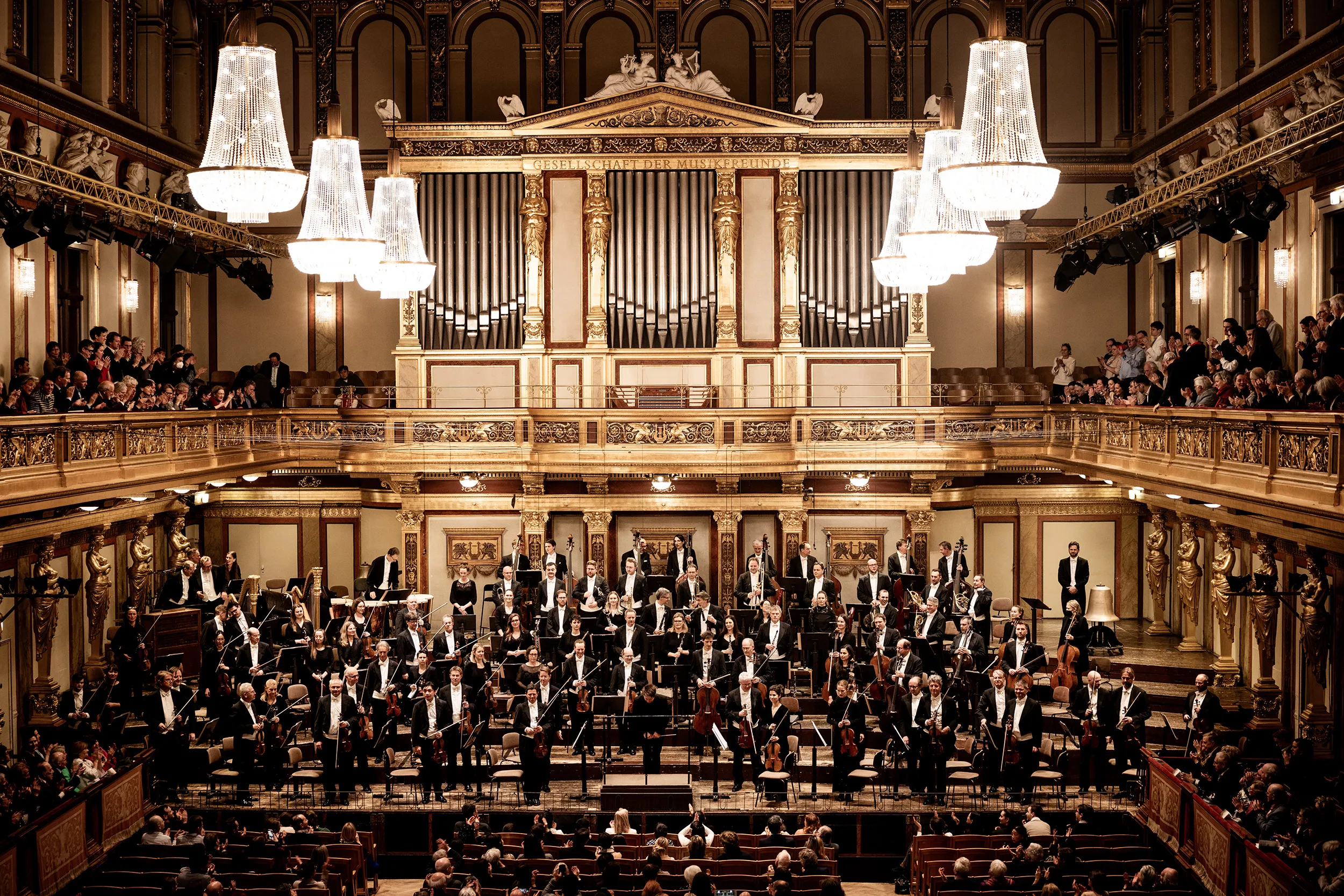 Orkiestra występująca w ozdobnej Złotej Sali Musikverein z żyrandolami i dużymi organami piszczałkowymi