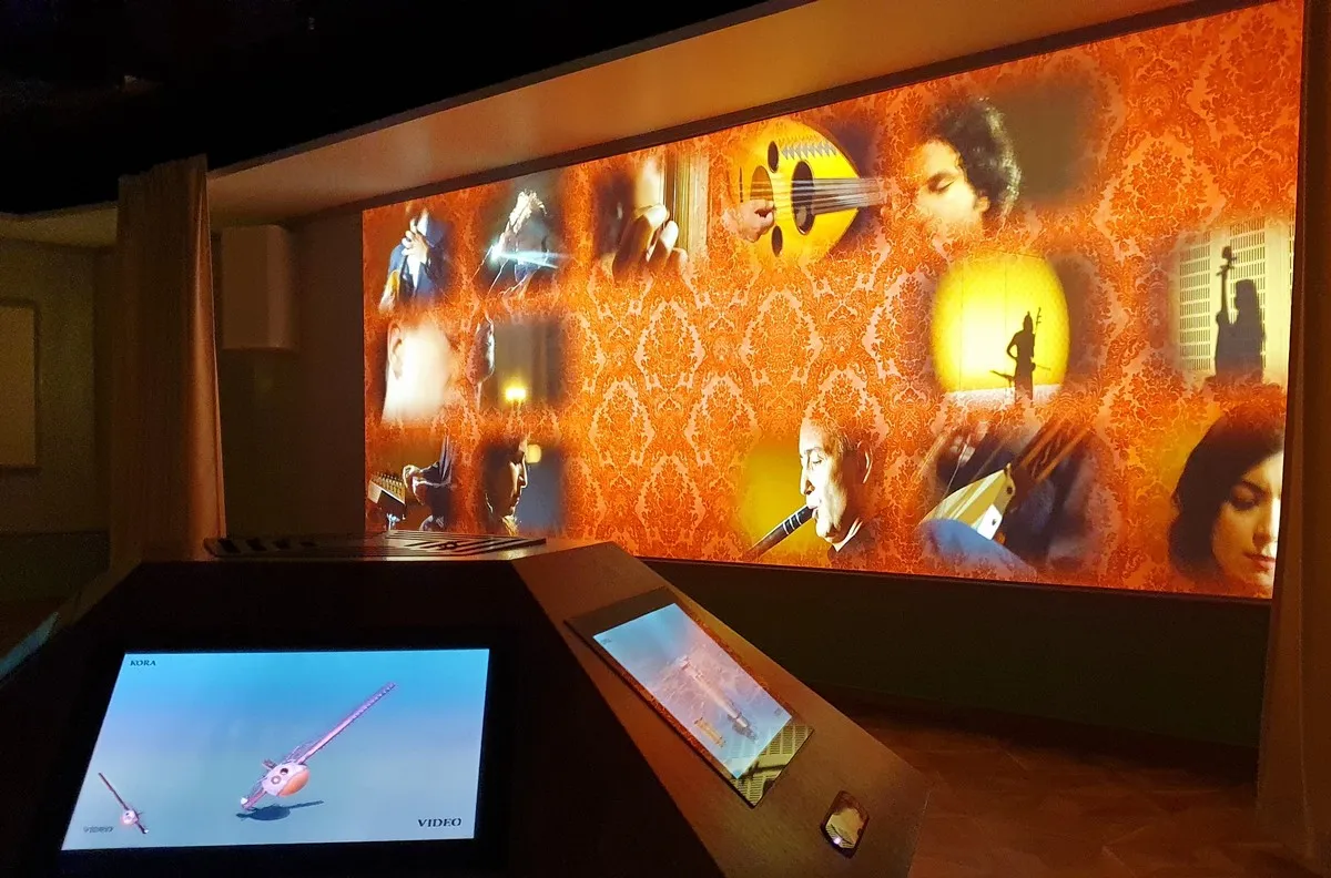 A large projection screen displaying a collage of images related to Mozart, including musical instruments and portraits, with interactive touchscreens in the foreground.