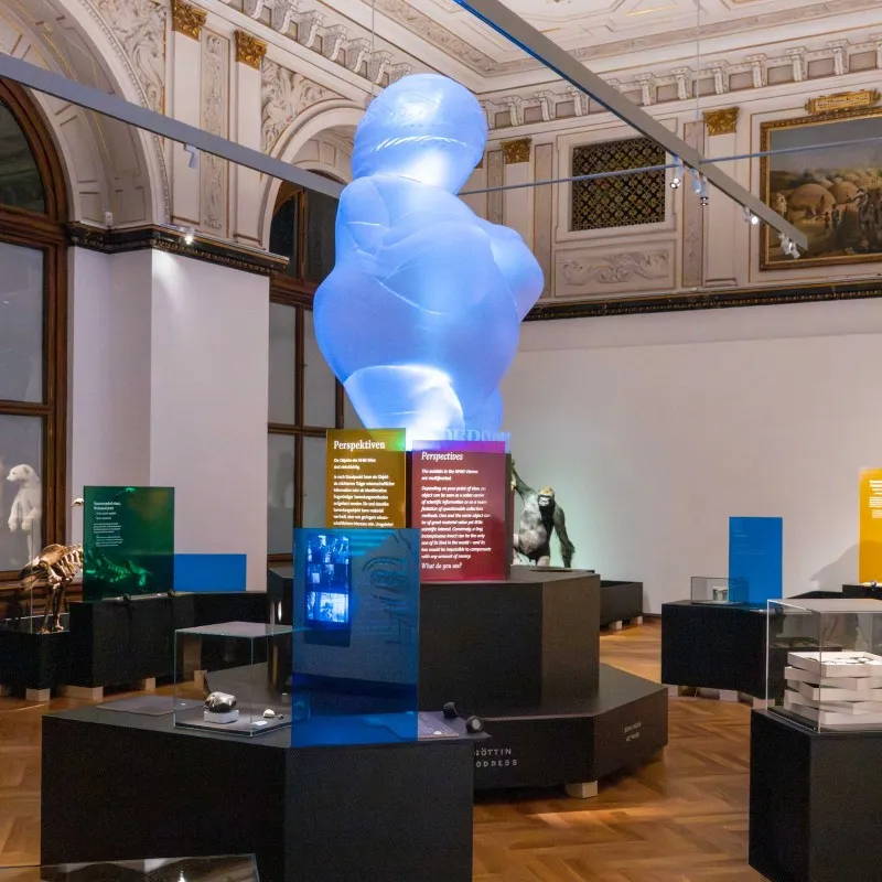 A blue translucent sculpture in a museum gallery with informational panels and display cases