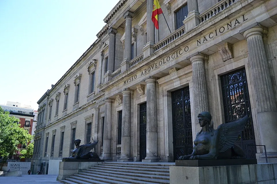 Neoclassicistisch gebouw met zuilen en stenen trappen, met het opschrift 'MUSEO ARQUEOLÓGICO NACIONAL' en twee sfinxen beelden bij de ingang