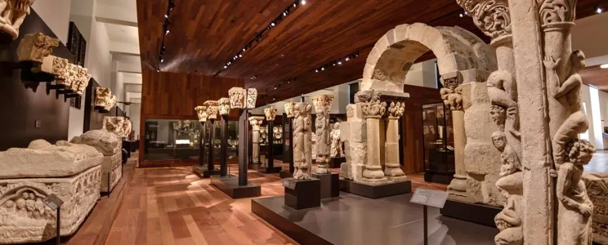 Interieur van het Nationaal Archeologisch Museum met stenen sculpturen en gesneden bogen tentoongesteld