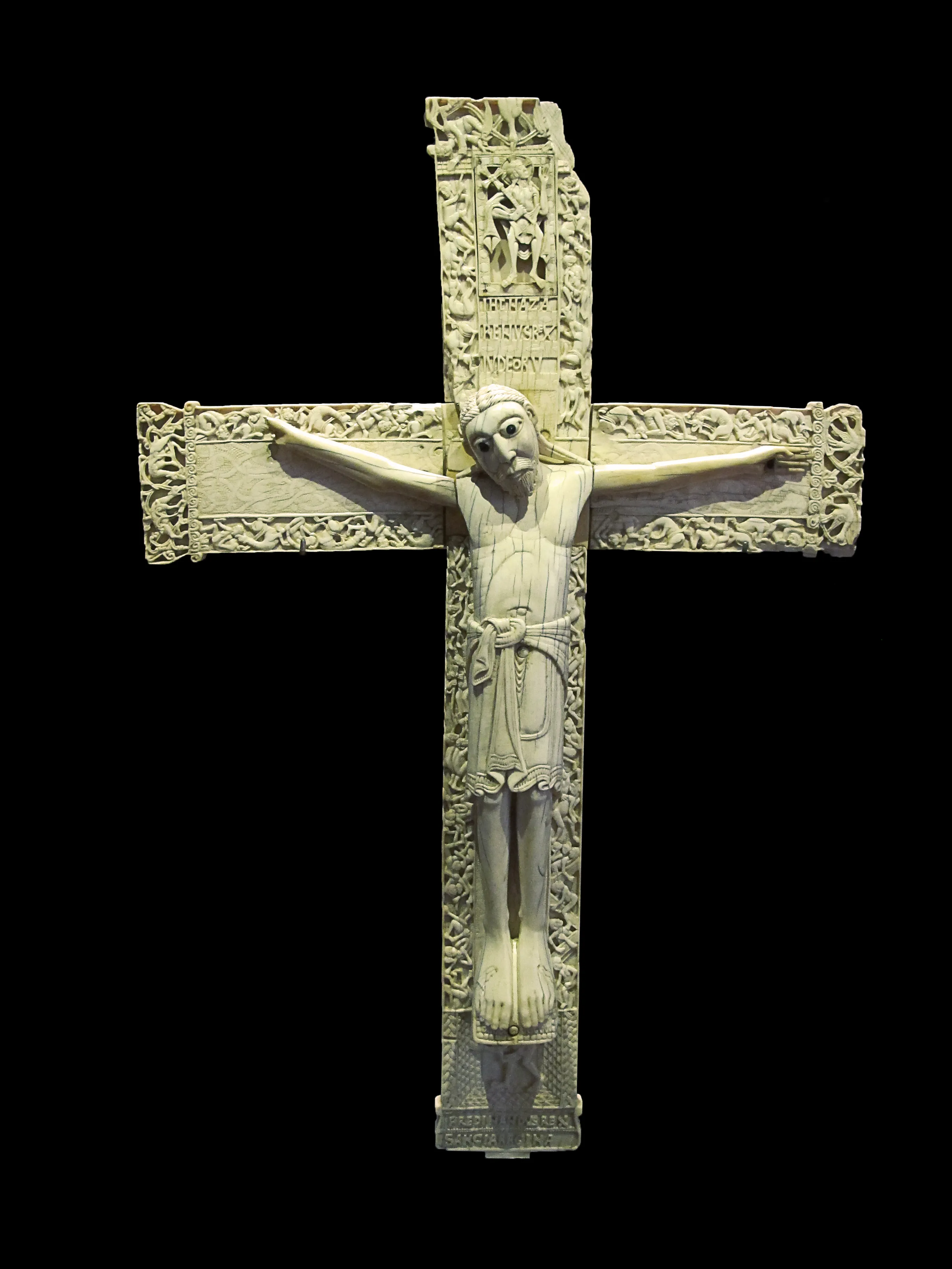 ivoorkruis met gesneden figuur van Christus aan het kruis tegen een zwarte achtergrond