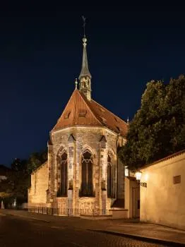 Gotisch kloostergebouw 's nachts met een hoge spits en boogramen, verlicht door warme lampen