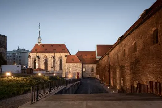 Gotisch klooster met een spits en rood pannendak verlicht bij schemering