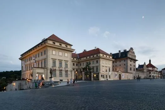 Salm Paleis op het Hradčany-plein met een rood pannendak en verlichte gevel onder een schemerige hemel