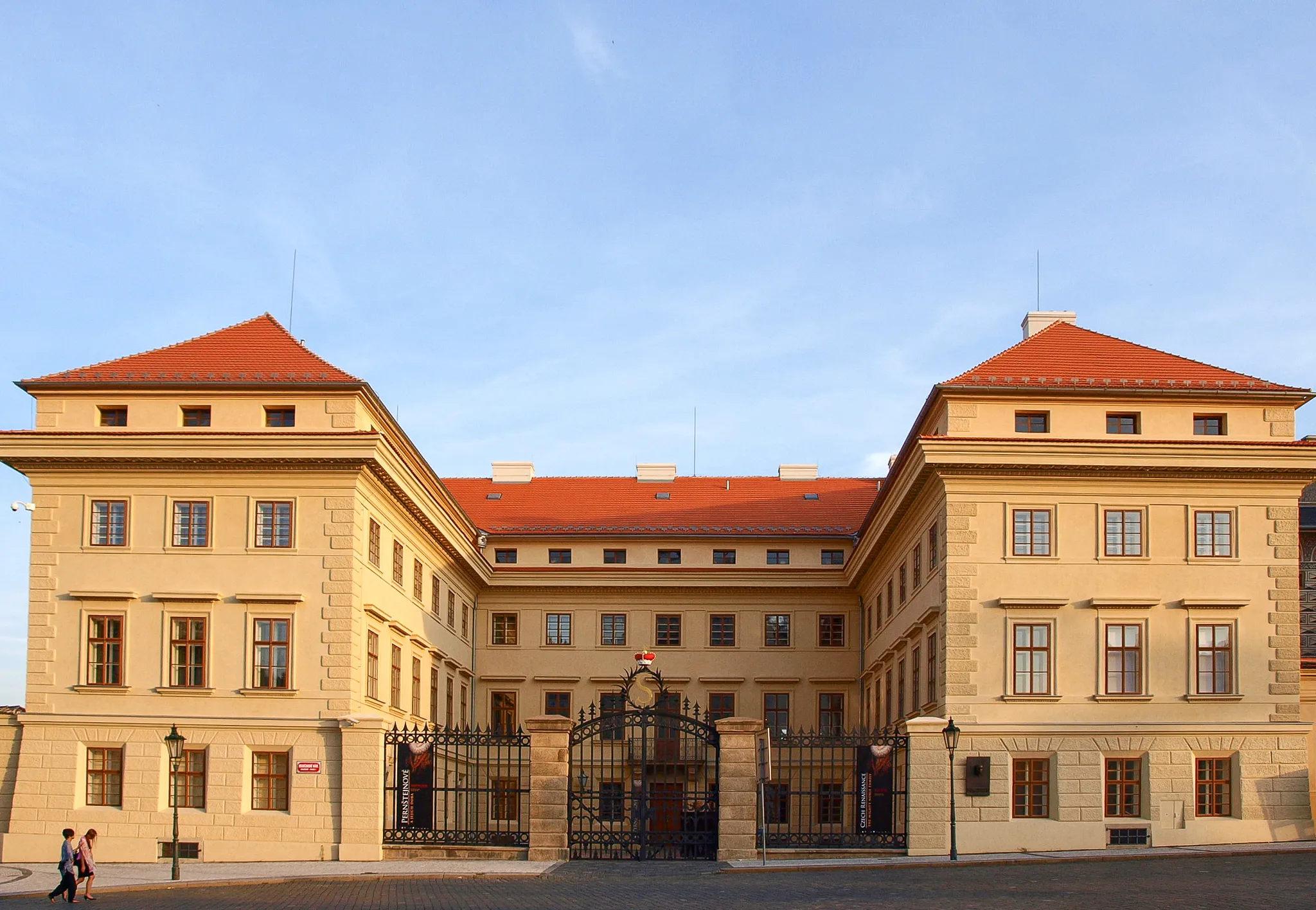 Salm Palace met gele stenen gevel, rood dak en zwarte ijzeren hekken onder een blauwe hemel
