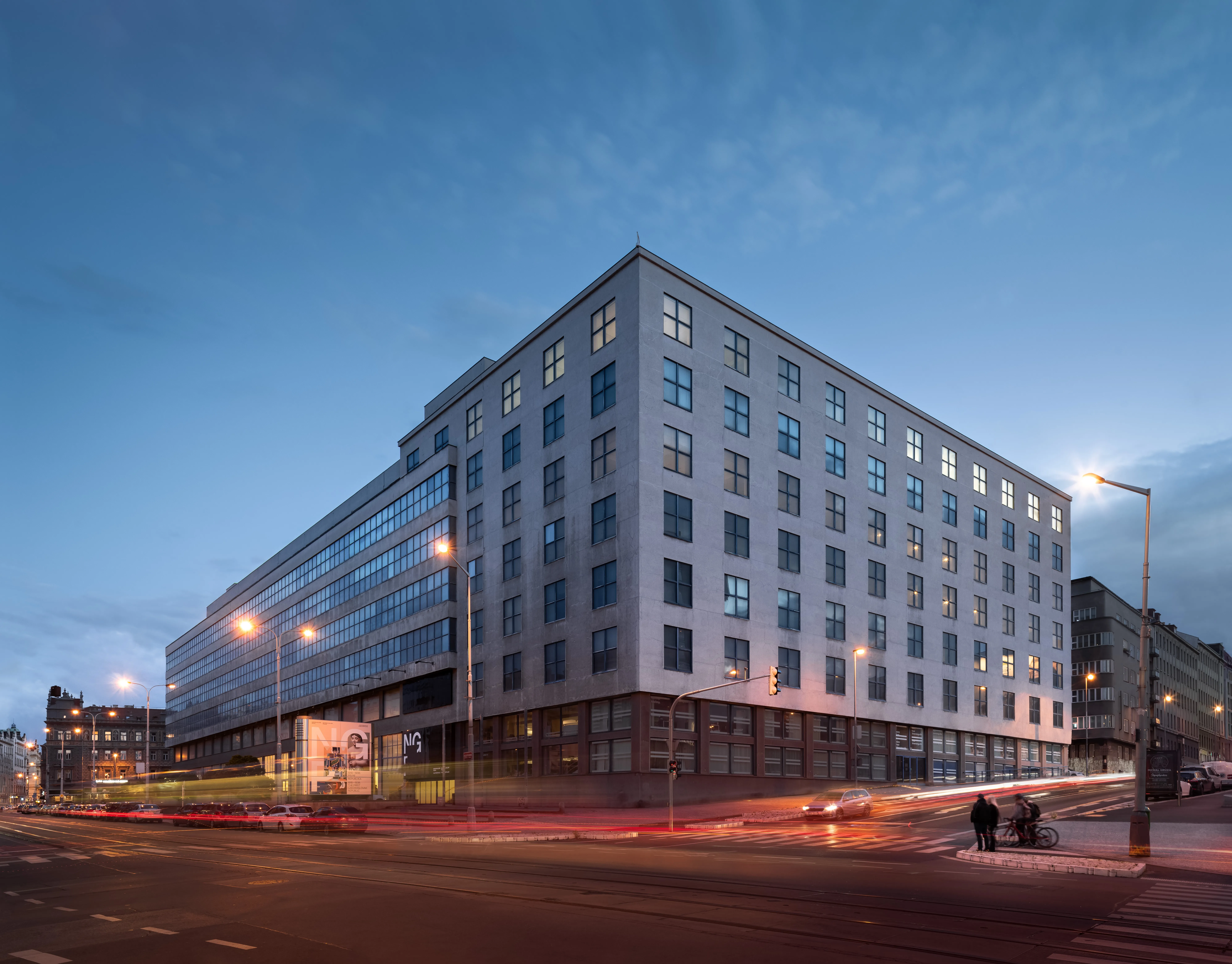 edificio moderno con fachada blanca y numerosas ventanas iluminadas al anochecer