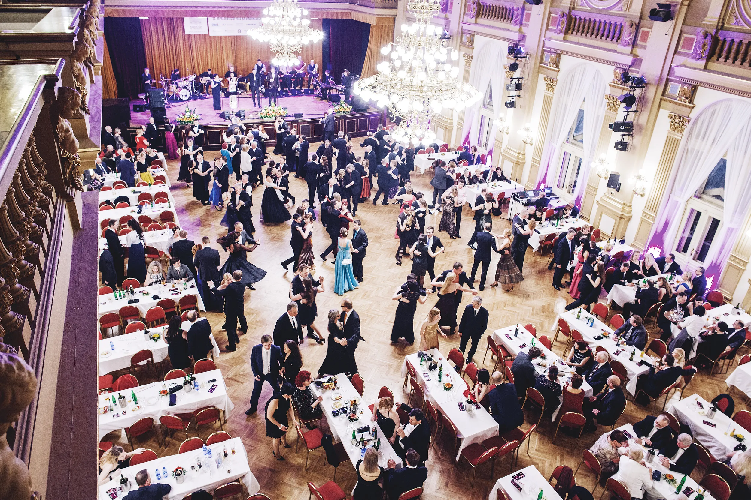 Large ballroom with chandeliers, tables, and people in formal wear at National House Vinohrady