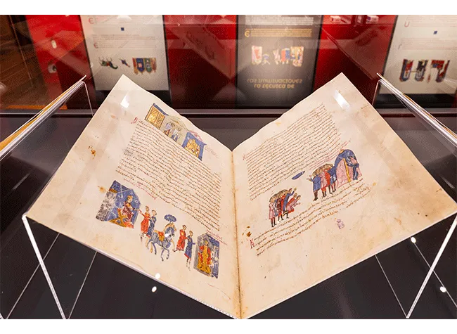 Otwarta iluminowana rękopis z kolorowymi ilustracjami i tekstem w szklanej gablocie