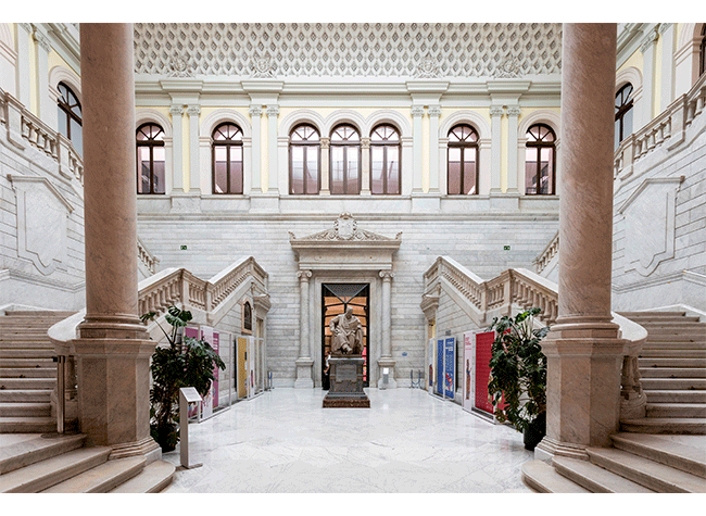 Wielka marmurowa sala z centralnymi schodami, dużymi kolumnami i ozdobnym sufitem w Museo de la Biblioteca Nacional