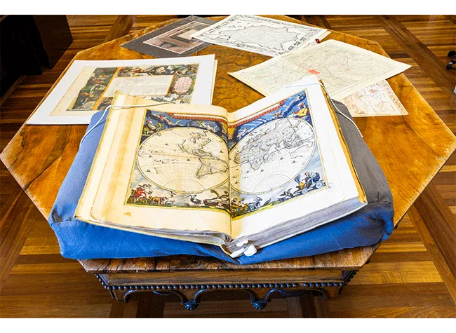 Otwórz historyczny manuskrypt ze szczegółowymi mapami i ilustracjami na drewnianym stole