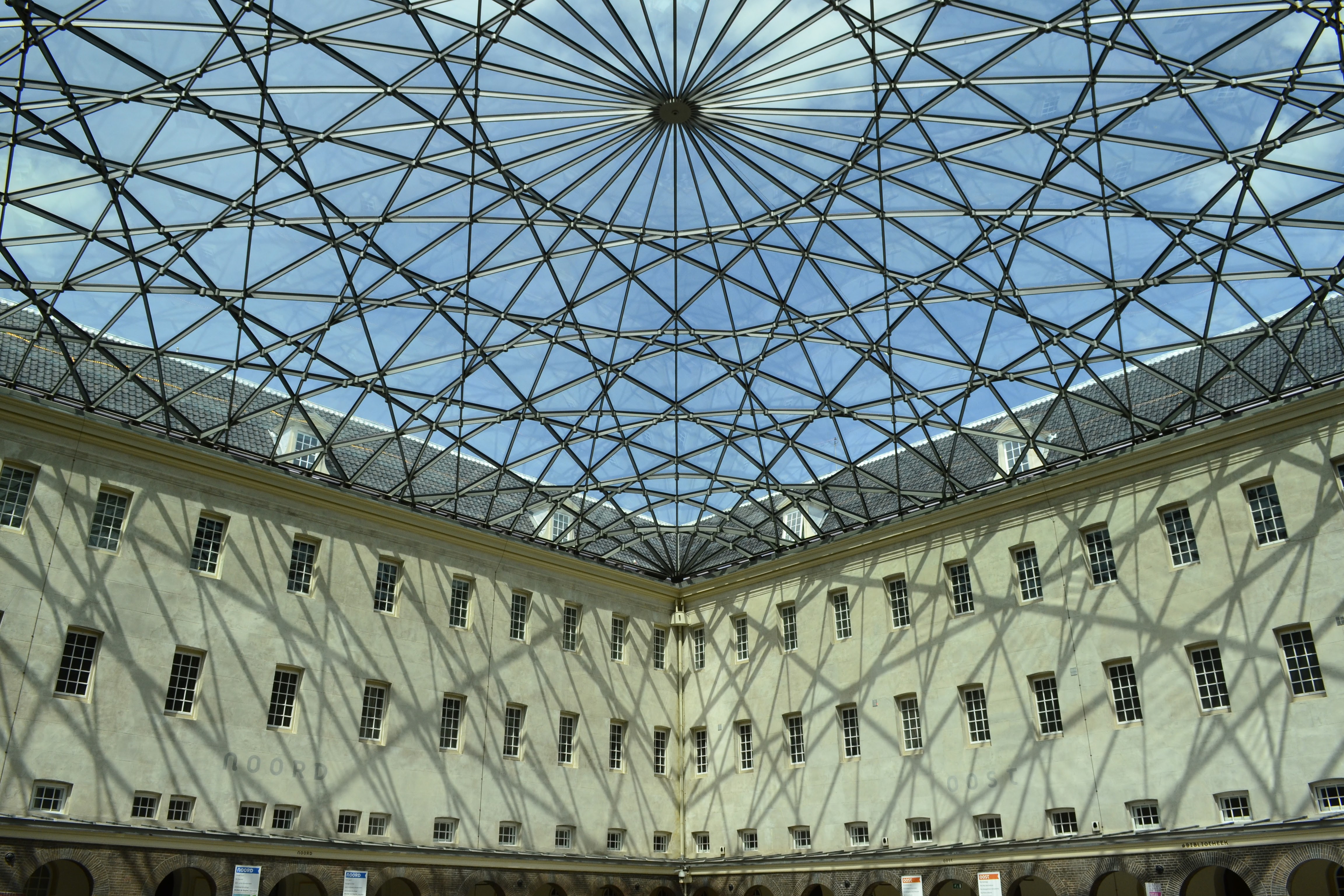 Geometric glass roof casting shadow patterns on the walls of a courtyard