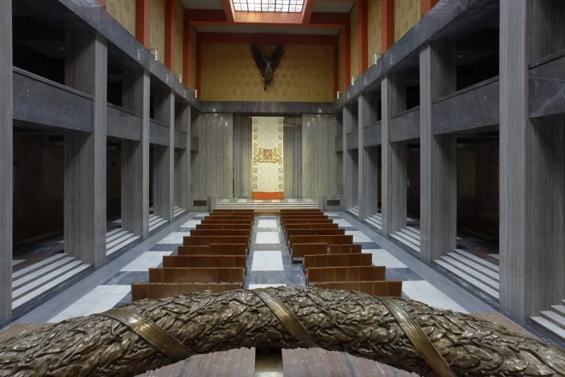Interior del Monumento Nacional en Vítkov con bancos de madera, columnas de hormigón y un altar central
