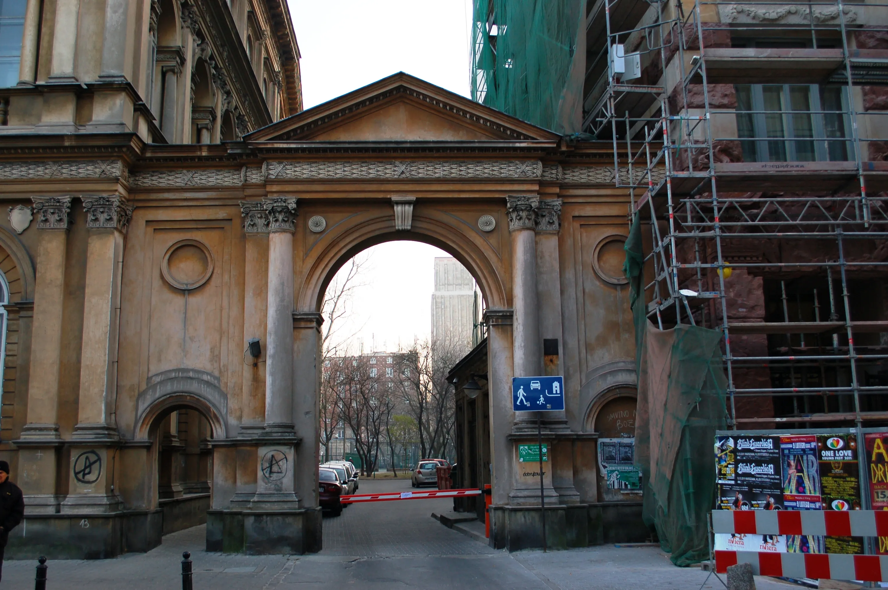 Entrada con un arco de piedra clásico a un edificio con andamios en el lado derecho