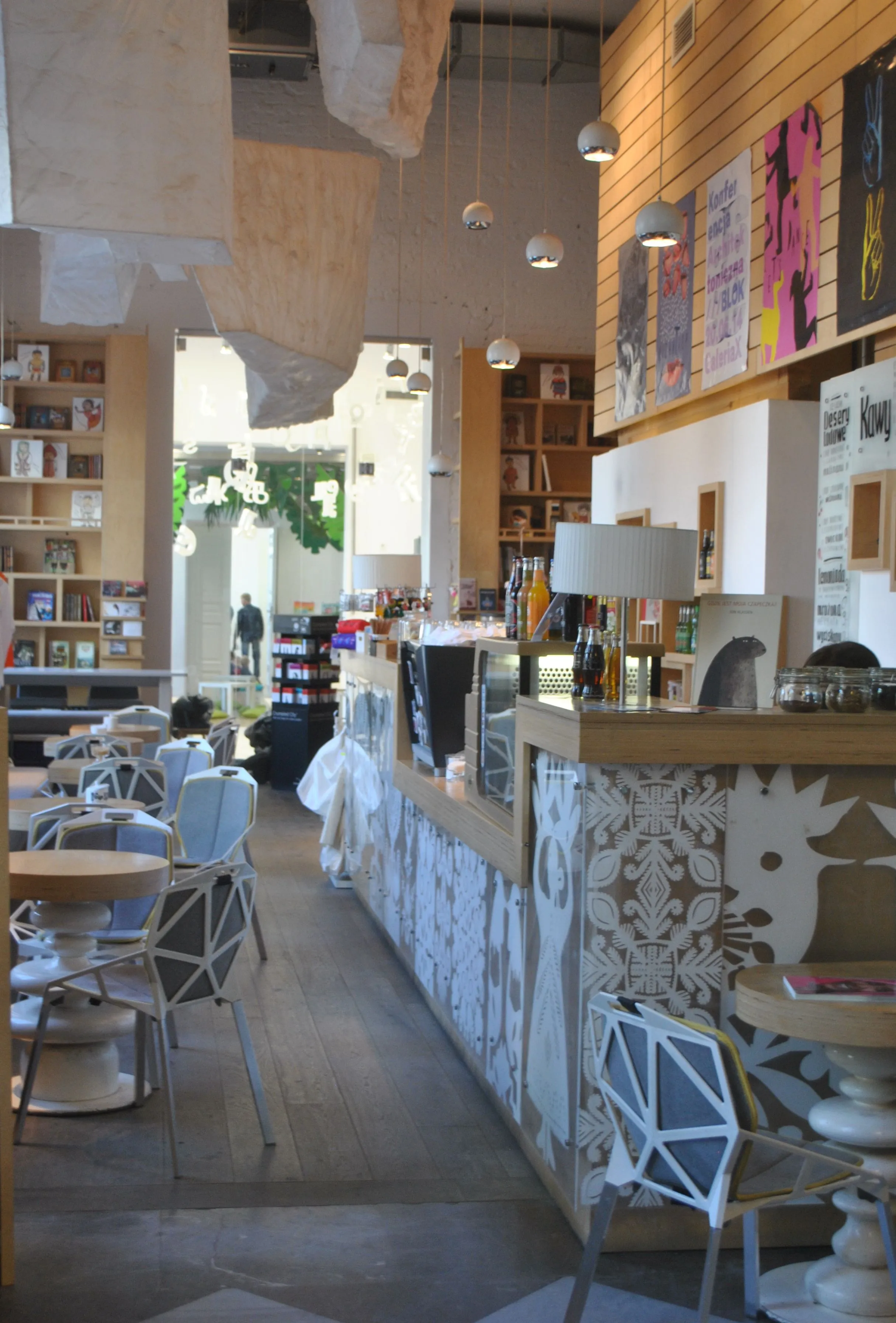 Interior de una cafetería moderna con suelos de madera, paredes blancas estampadas y mobiliario contemporáneo en el Museo Nacional de Etnografía de Varsovia