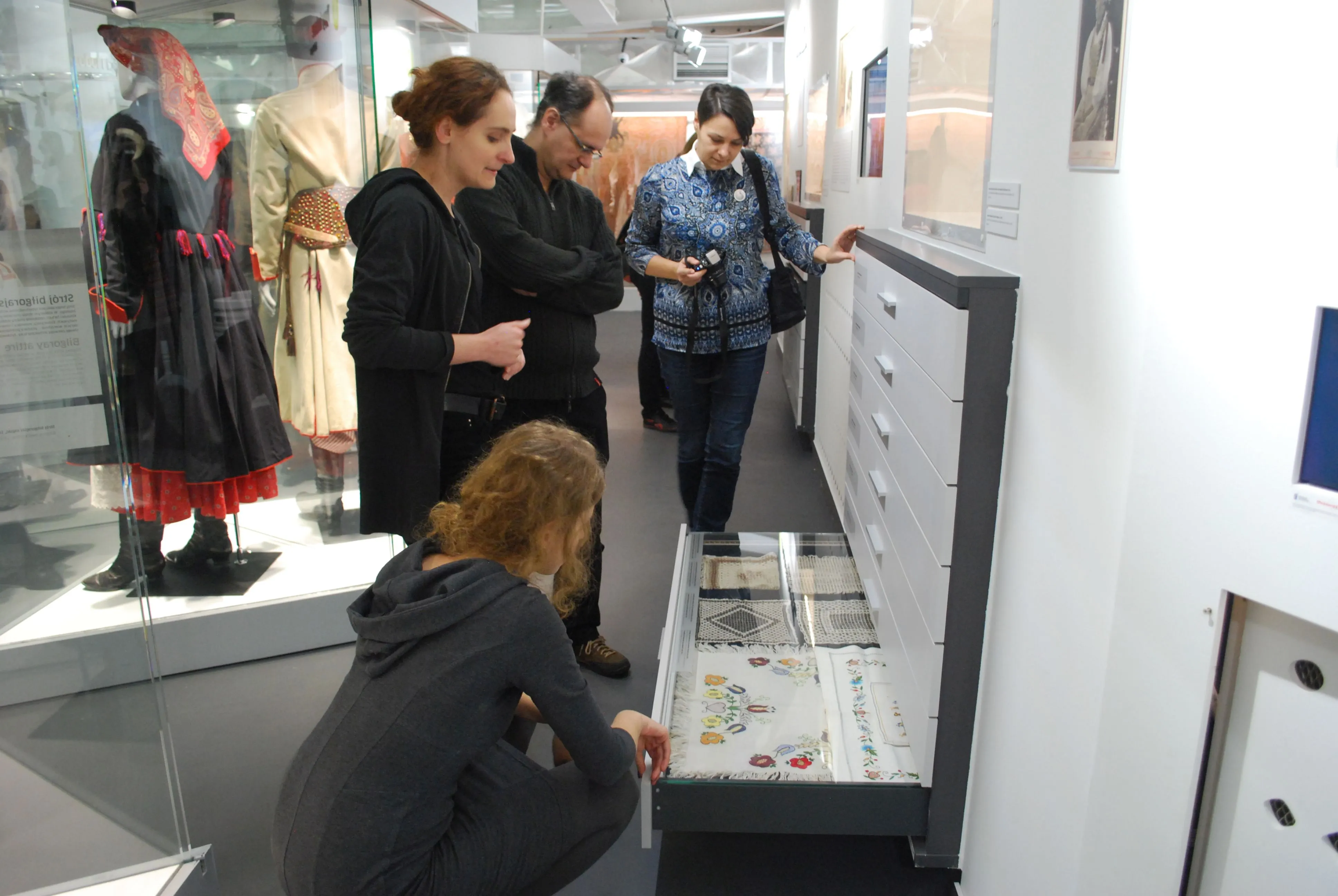 Visitantes observando una vitrina de cristal con artefactos tradicionales en una galería de museo