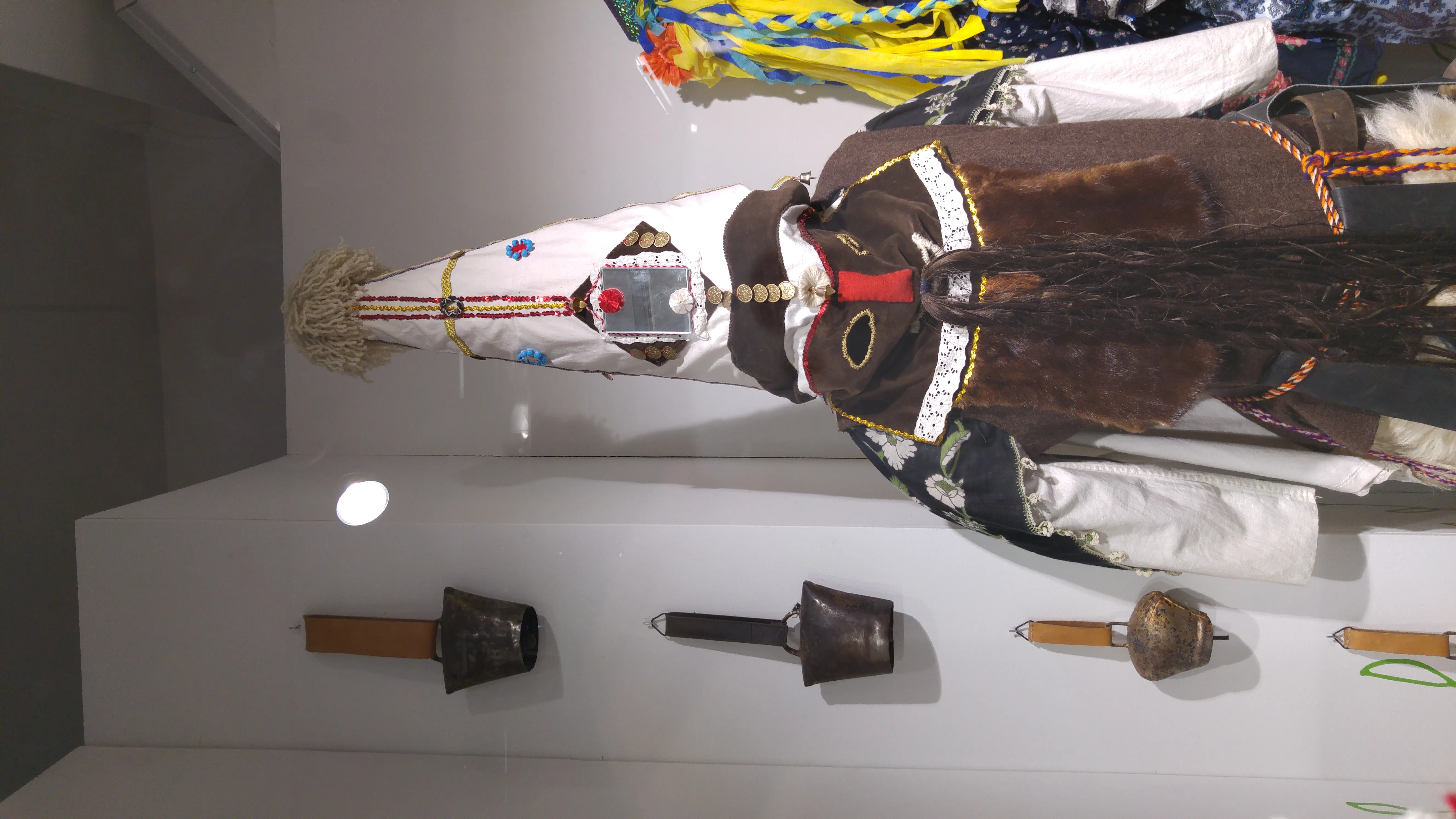 Traje tradicional con tocado decorado y objetos ceremoniales en exhibición en una galería de museo