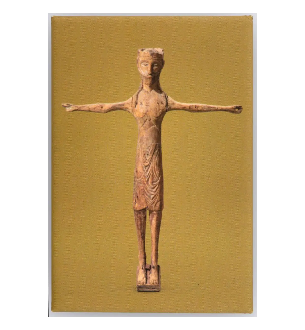 Carved wooden standing figure with outstretched arms and draped clothing, photographed against a yellowish-olive background
