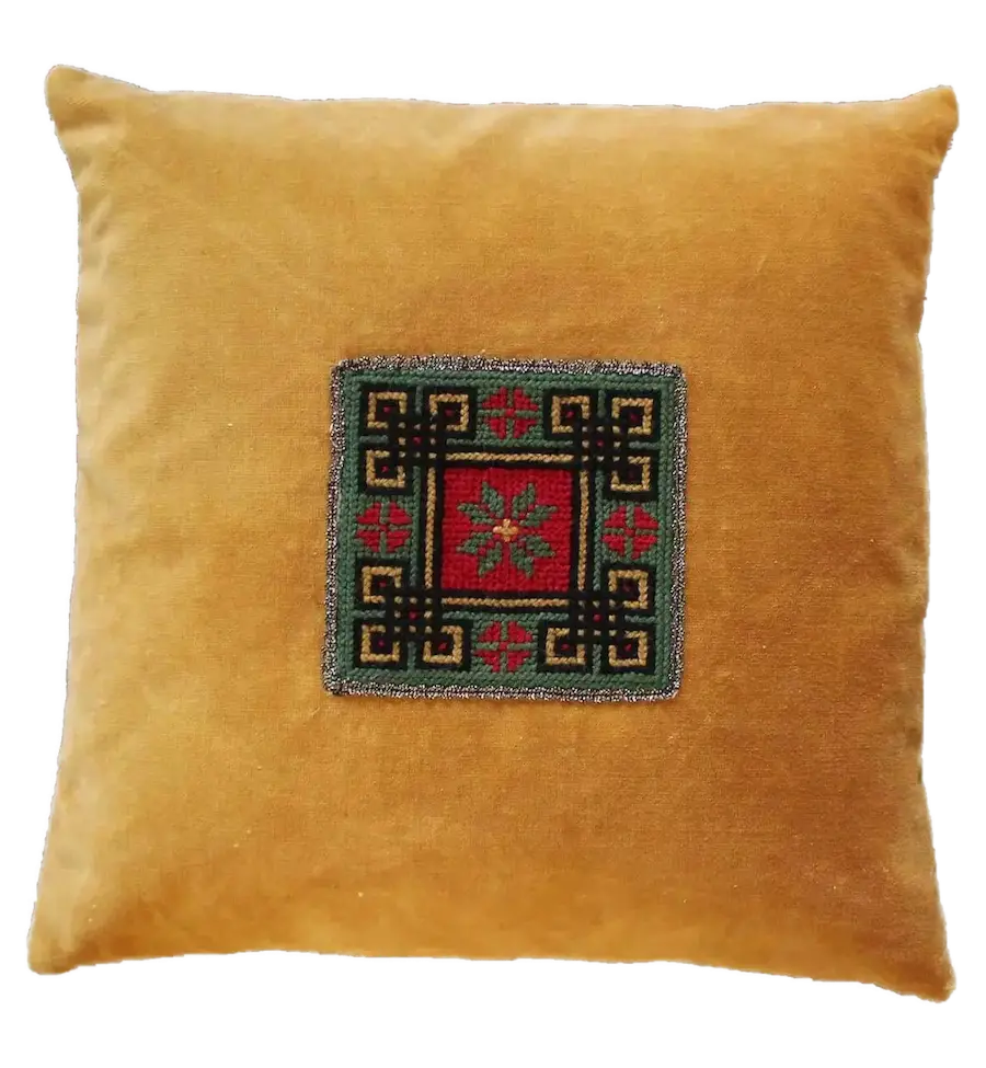 Yellow velvet cushion with a square embroidered geometric pattern in red, green, and black at the center