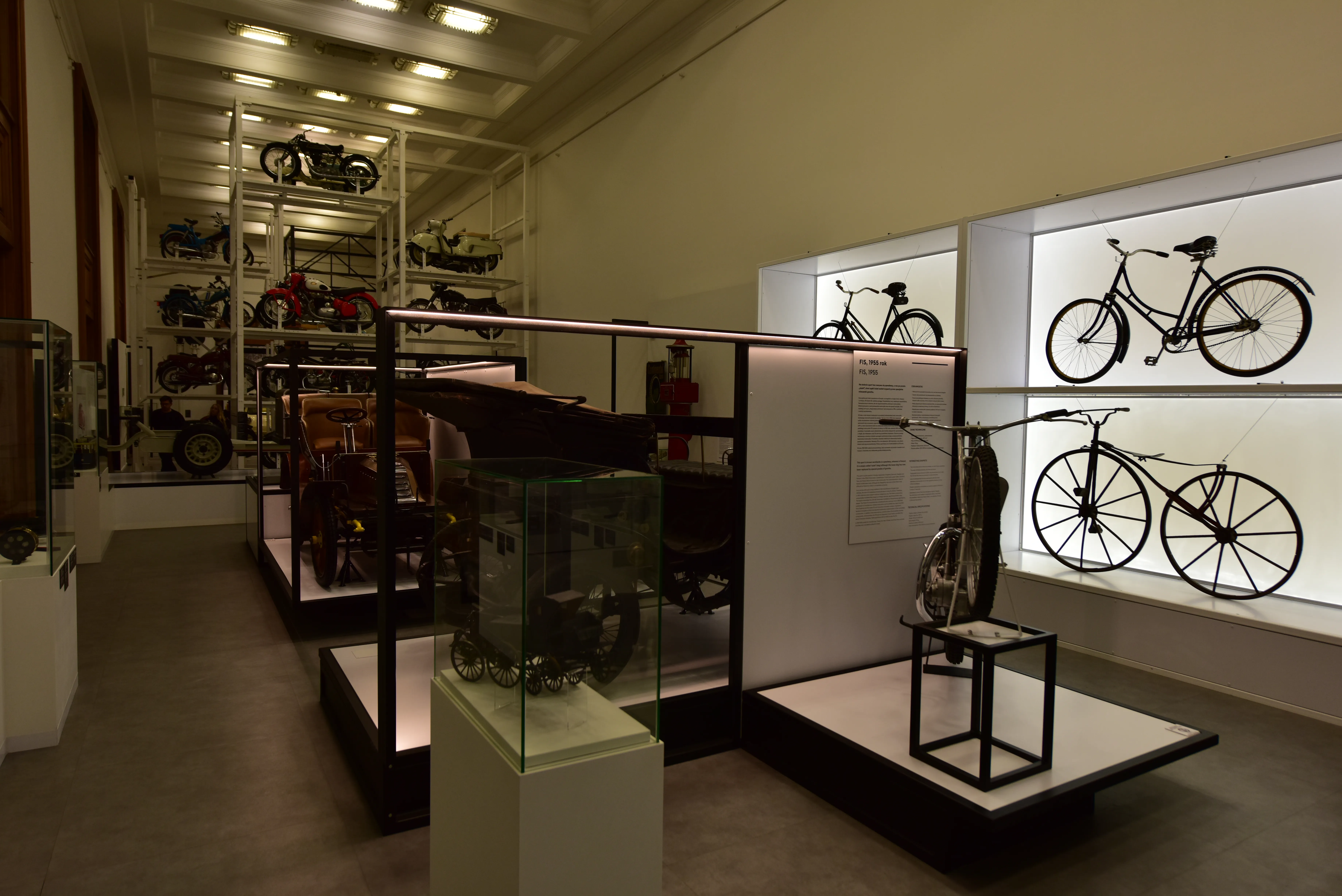 Interior de un museo con bicicletas en exhibición en vitrinas y en paneles de pared