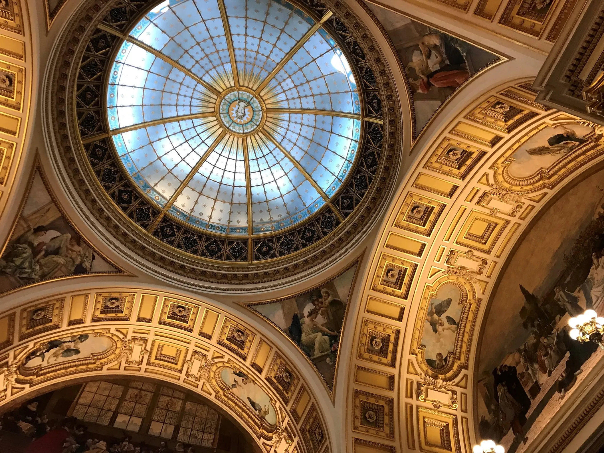 Ornate interieurplafond met een grote glazen koepel en gouden decoratieve elementen