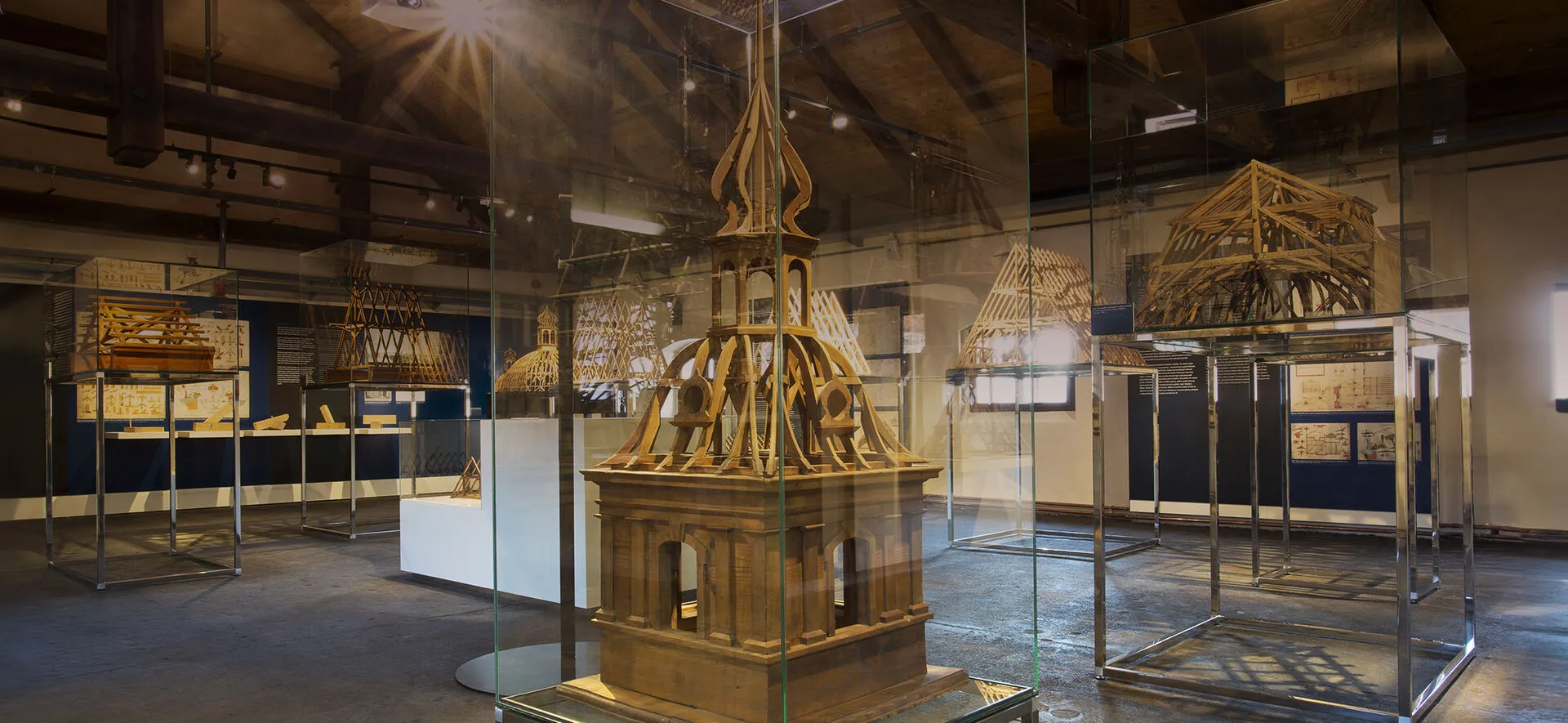 A wooden model of a tower inside a glass display case in a museum hall