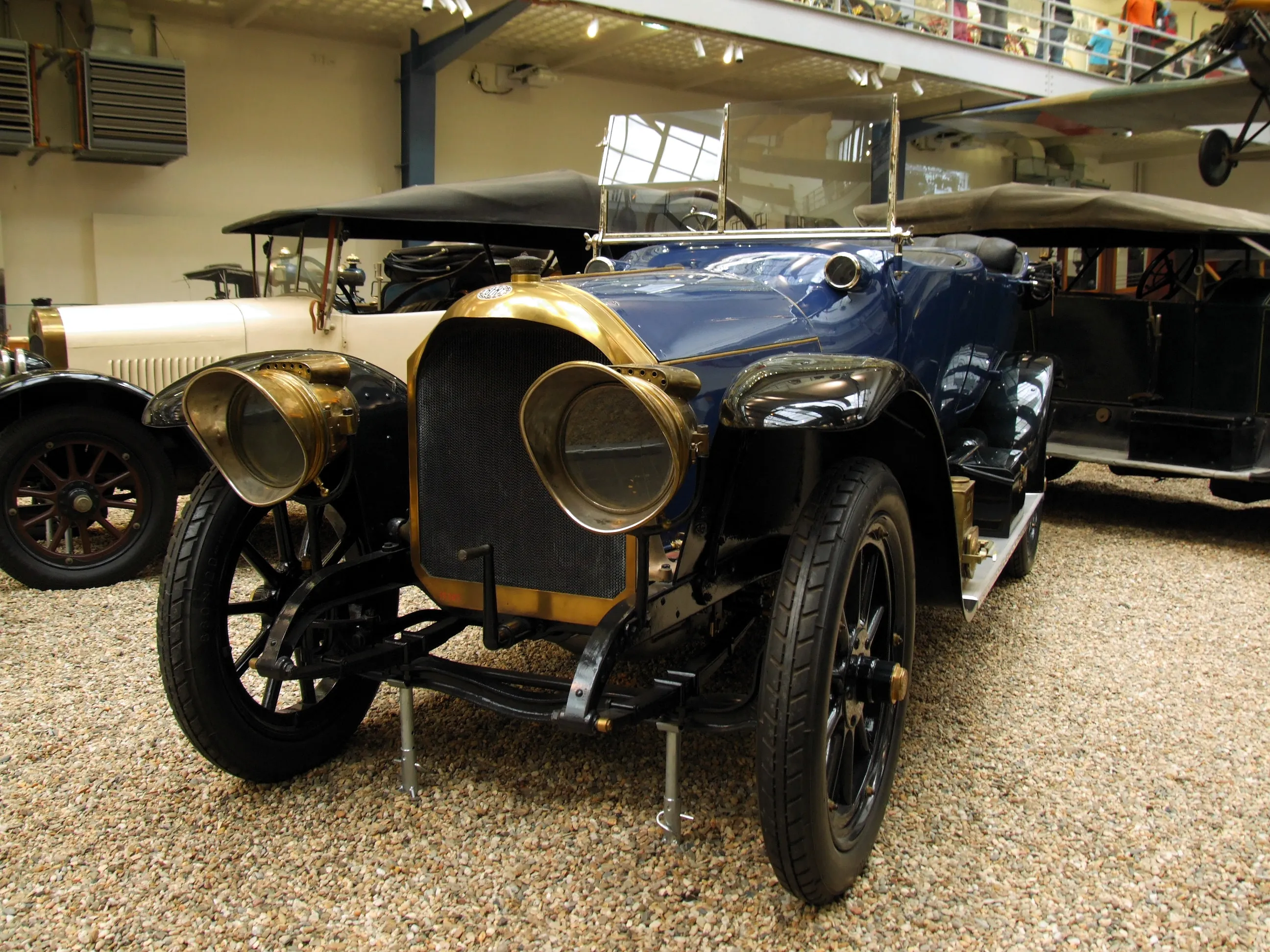 A vintage blue Benz 16-40 HP automobile with brass headlights and black wheels on display indoors.
