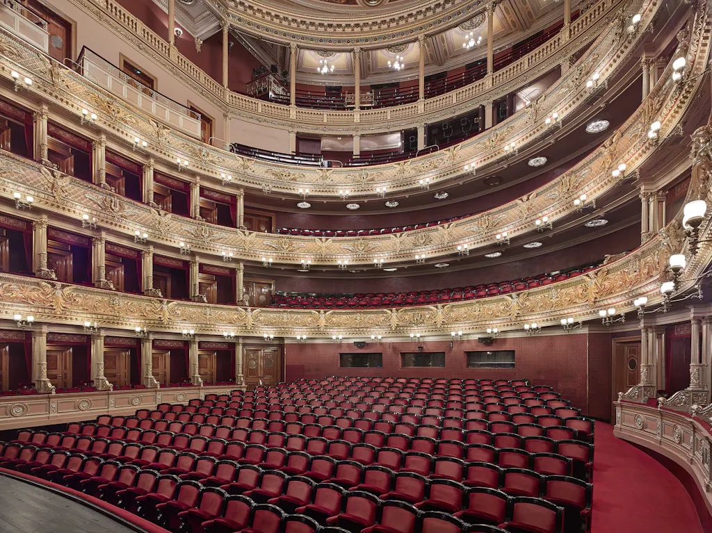 Interior of the National Theatre with red seats, ornate balconies, and golden decorations
