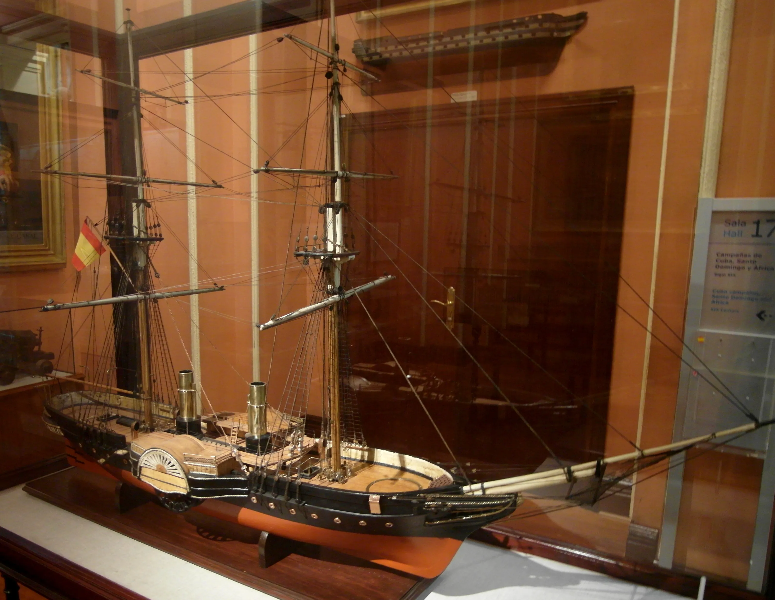 A ship model with multiple masts and rigging displayed in a glass case