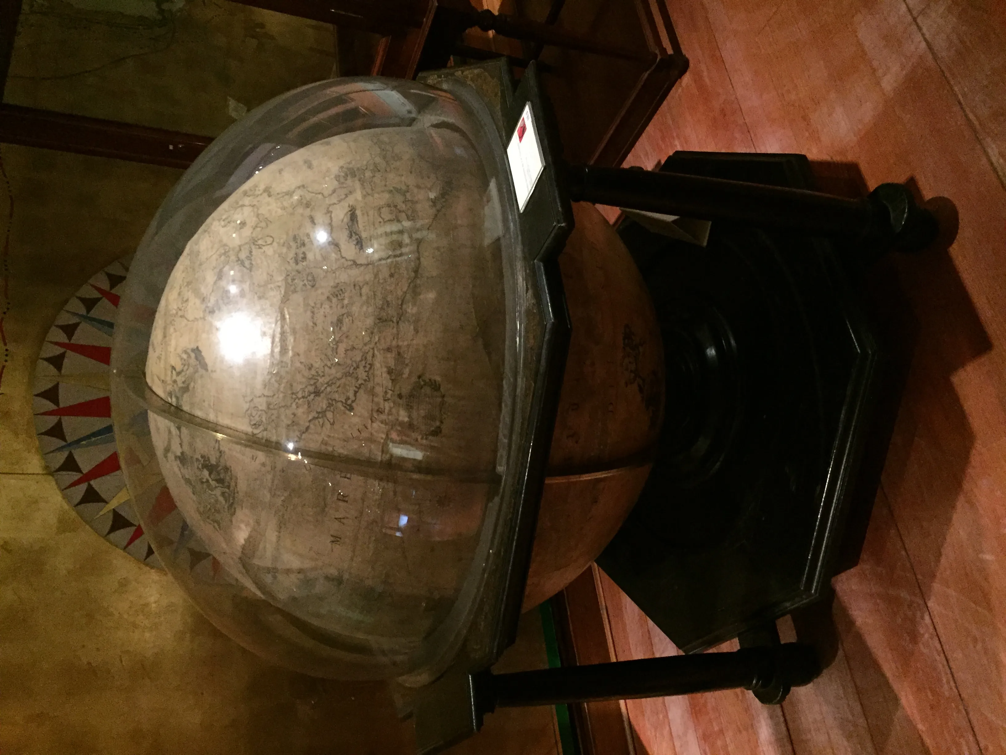 Large antique globe encased in a transparent dome on a black stand