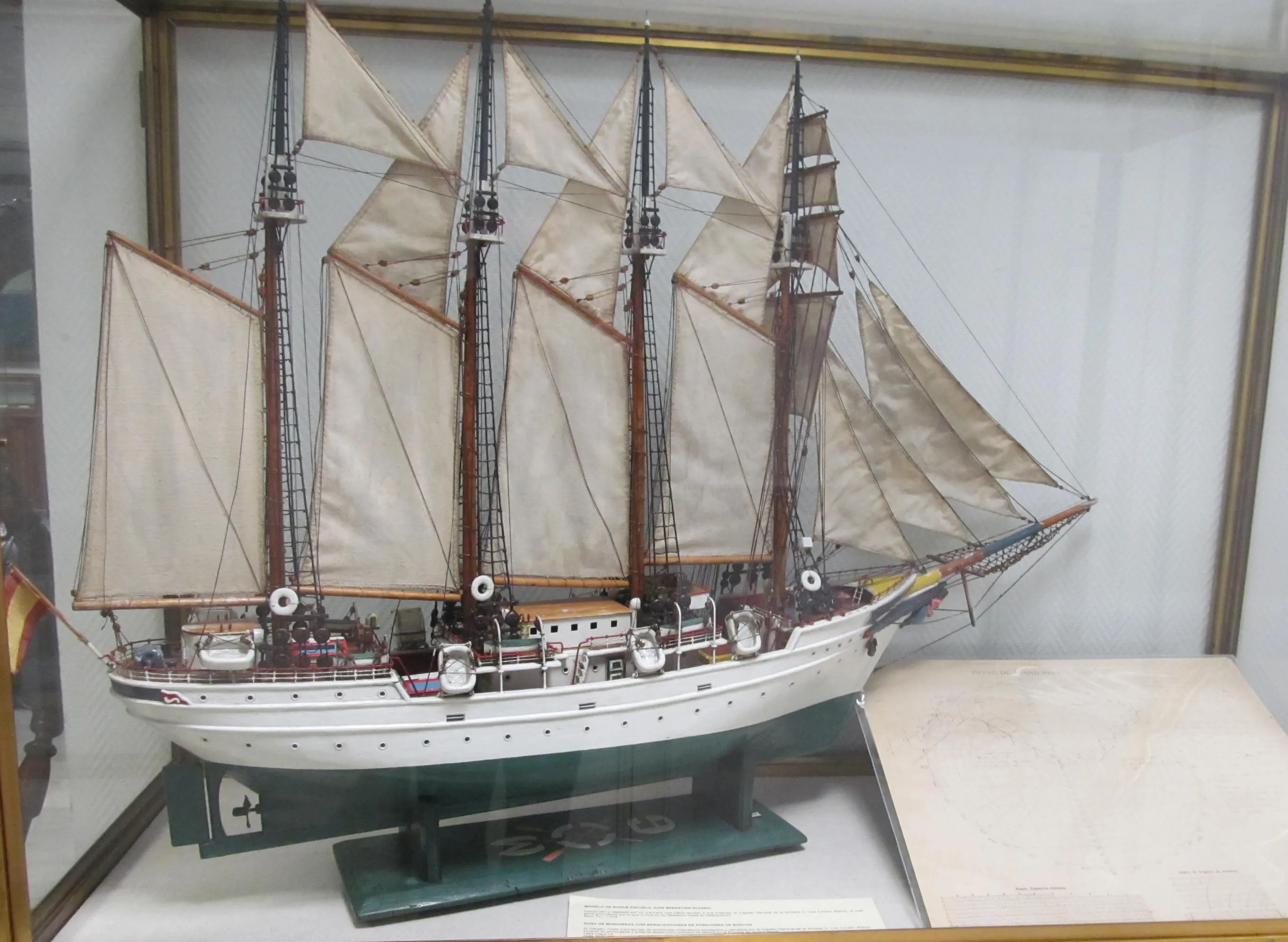 A large ship model with multiple masts and sails displayed in a glass case