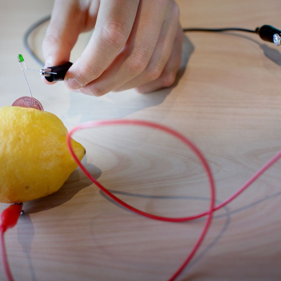Hand die draden verbindt met een citroen in een interactieve wetenschapstentoonstelling die elektriciteitsopwekking demonstreert