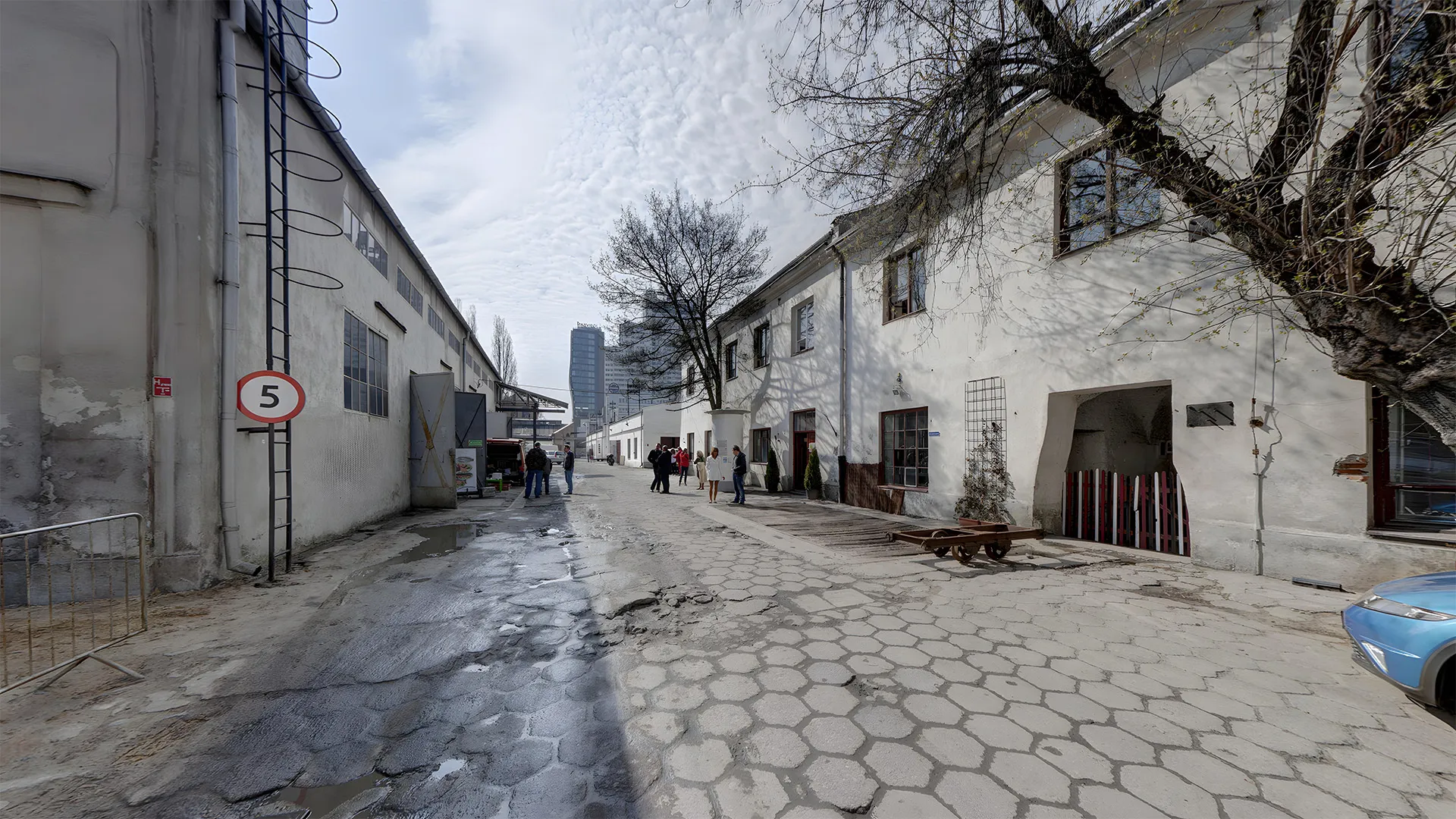 Patio del Museo Norblin Factory con edificios industriales, un camino de adoquines y una señal de 5 km/h
