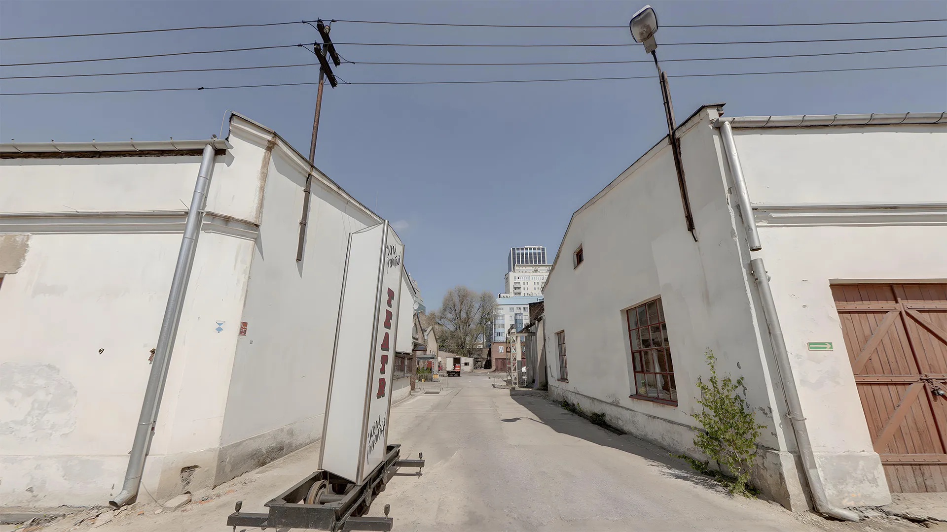 edificios industriales blancos en un callejón con cables eléctricos por encima