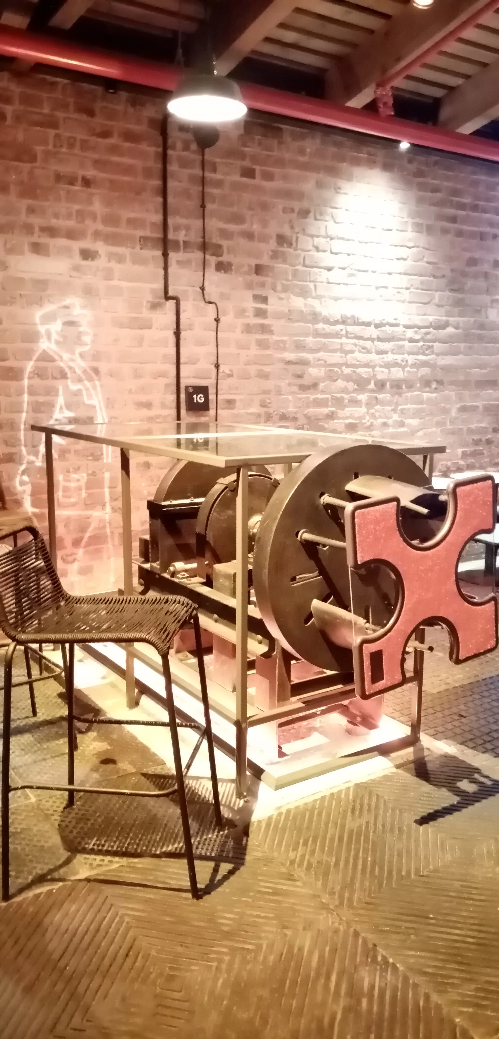exposición de maquinaria industrial con componentes metálicos rojos y un fondo de pared de ladrillos