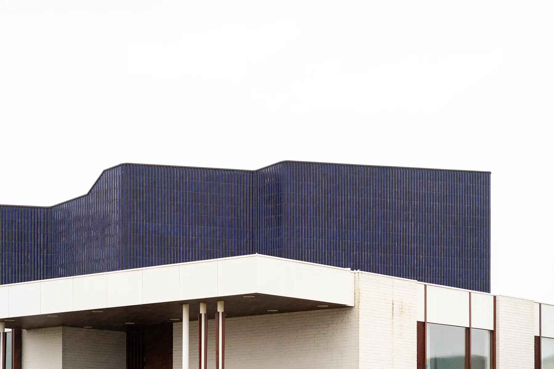 Architectural exterior of the Nordic House showing a dark blue textured upper facade above a white concrete structure with columns and windows