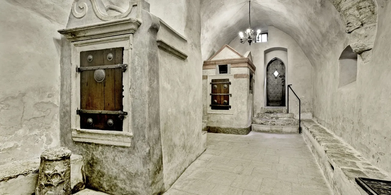 pasillo de piedra con techo abovedado y puertas de madera dentro de la Sinagoga Vieja-Nueva