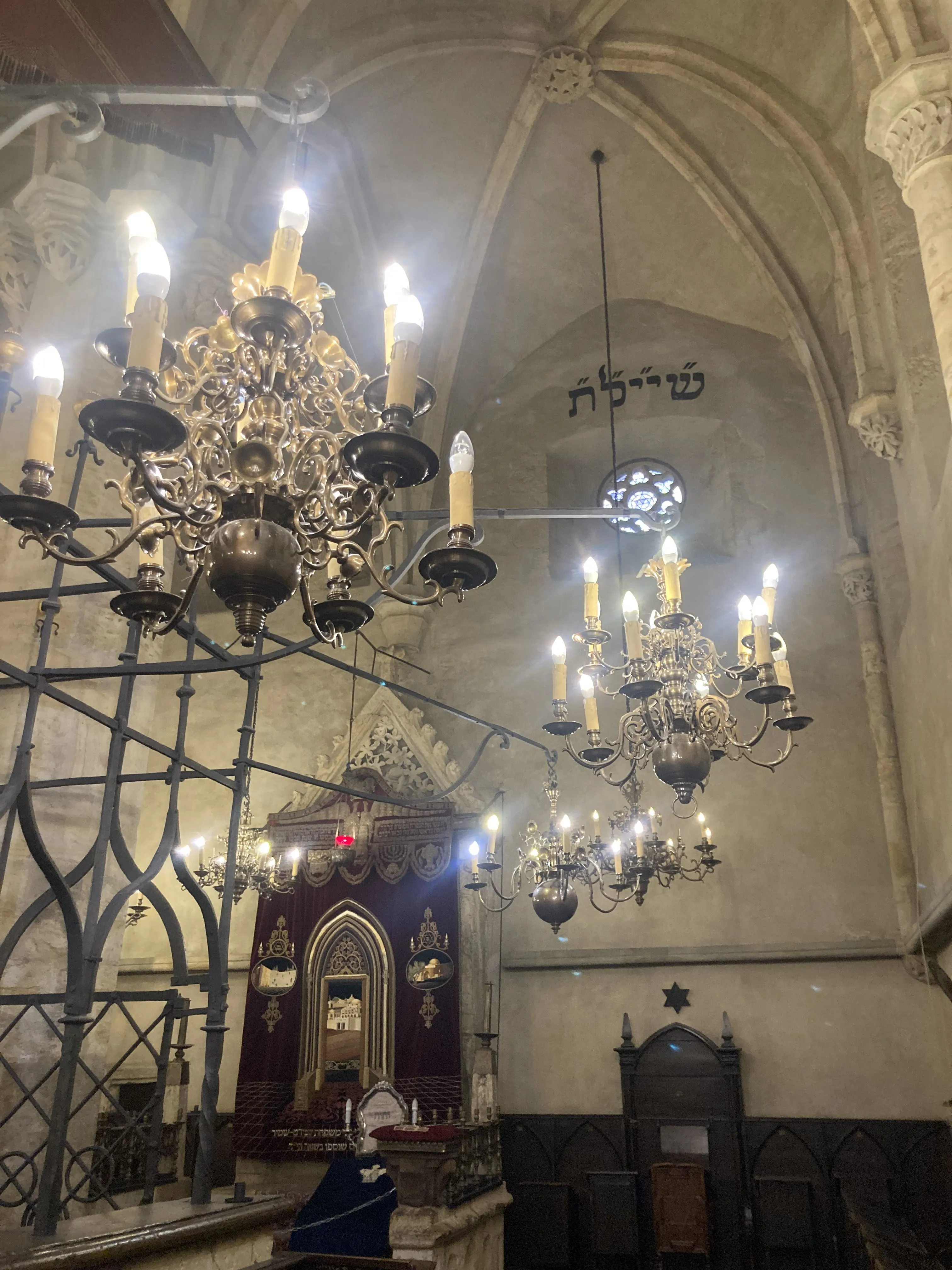 Interior de la Sinagoga Vieja-Nueva con candelabros, techos abovedados y un arca de la Torá