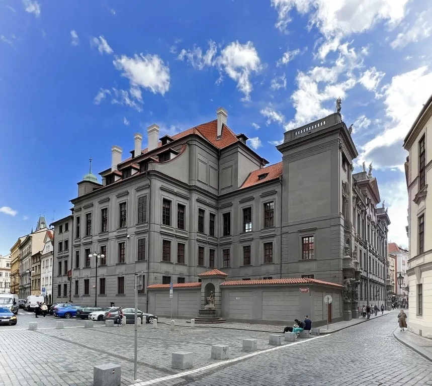 historic building with grey facade and red roof under blue sky