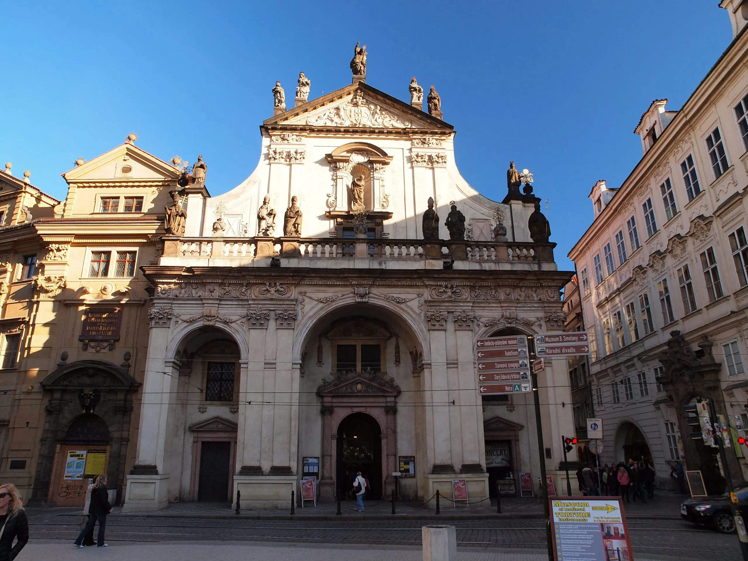 Gothic facade of the Old Town Bridge Tower with statues and arched entrances under a clear blue sky