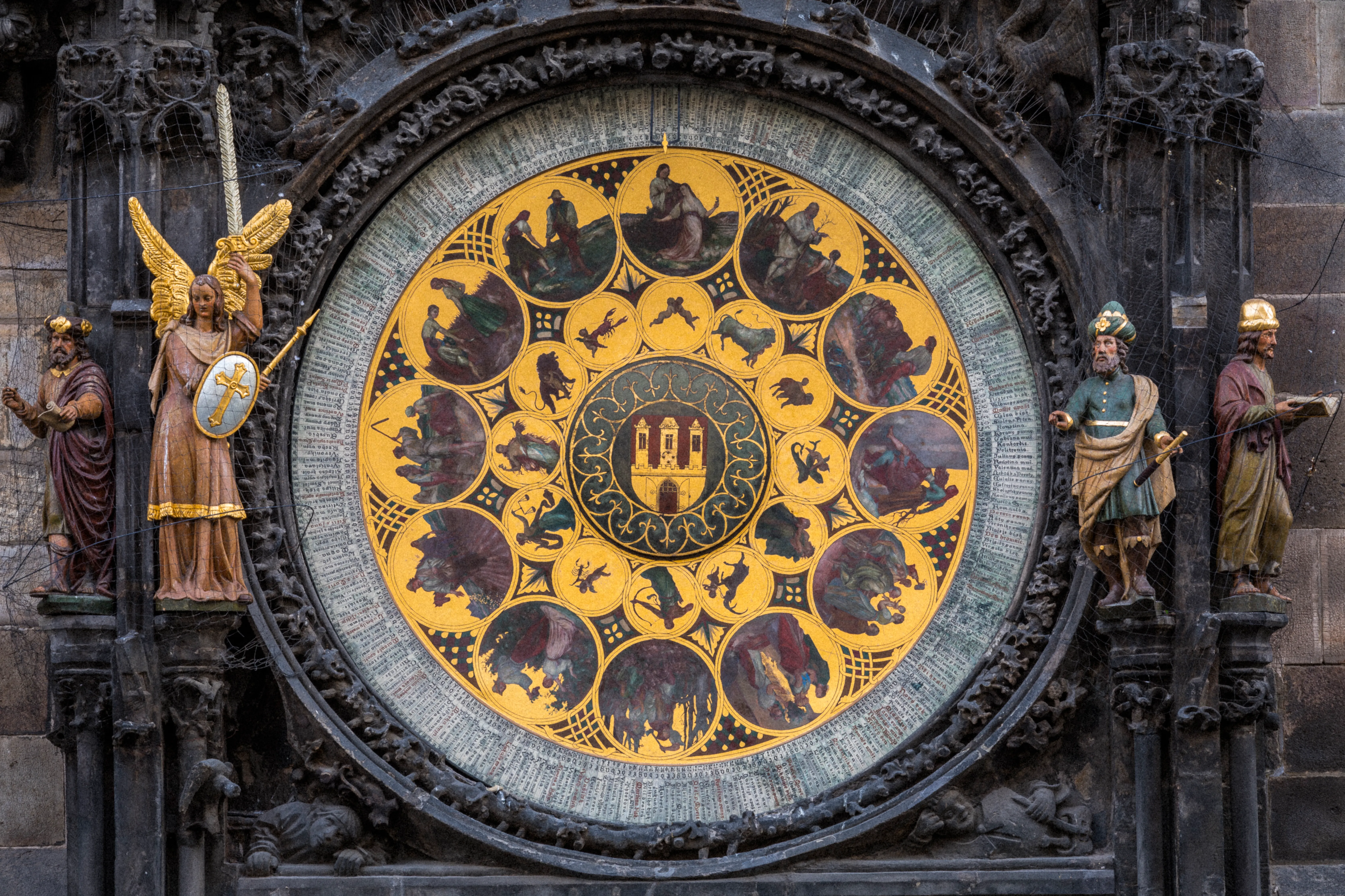 Zbliżenie na praski zegar astronomiczny ze złotą tarczą, symbolami zodiaku i posągami
