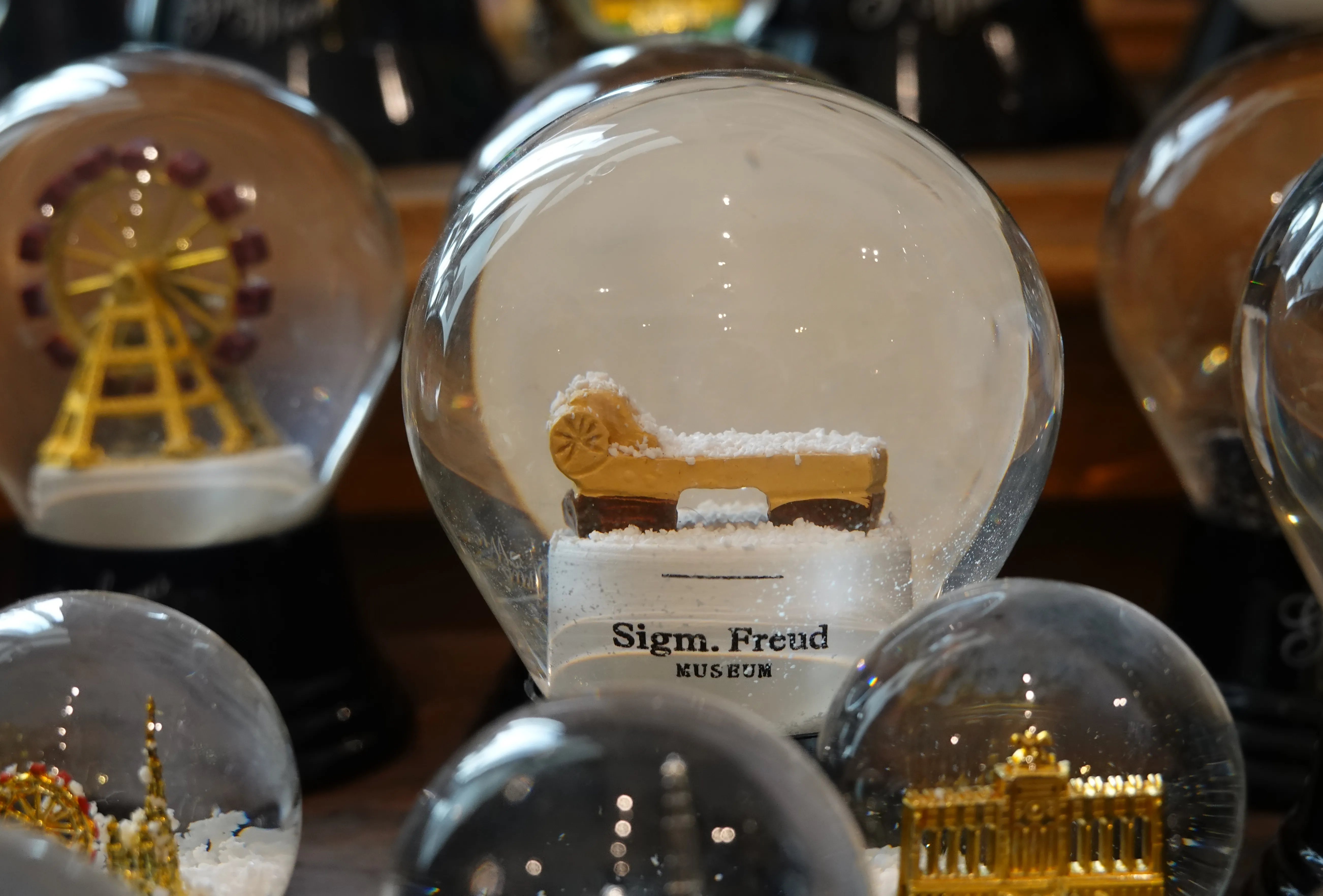 Viennese snow globes on display, featuring miniature scenes including a Ferris wheel and a building, with a label reading 'Sigm. Frend MUSEUM'.