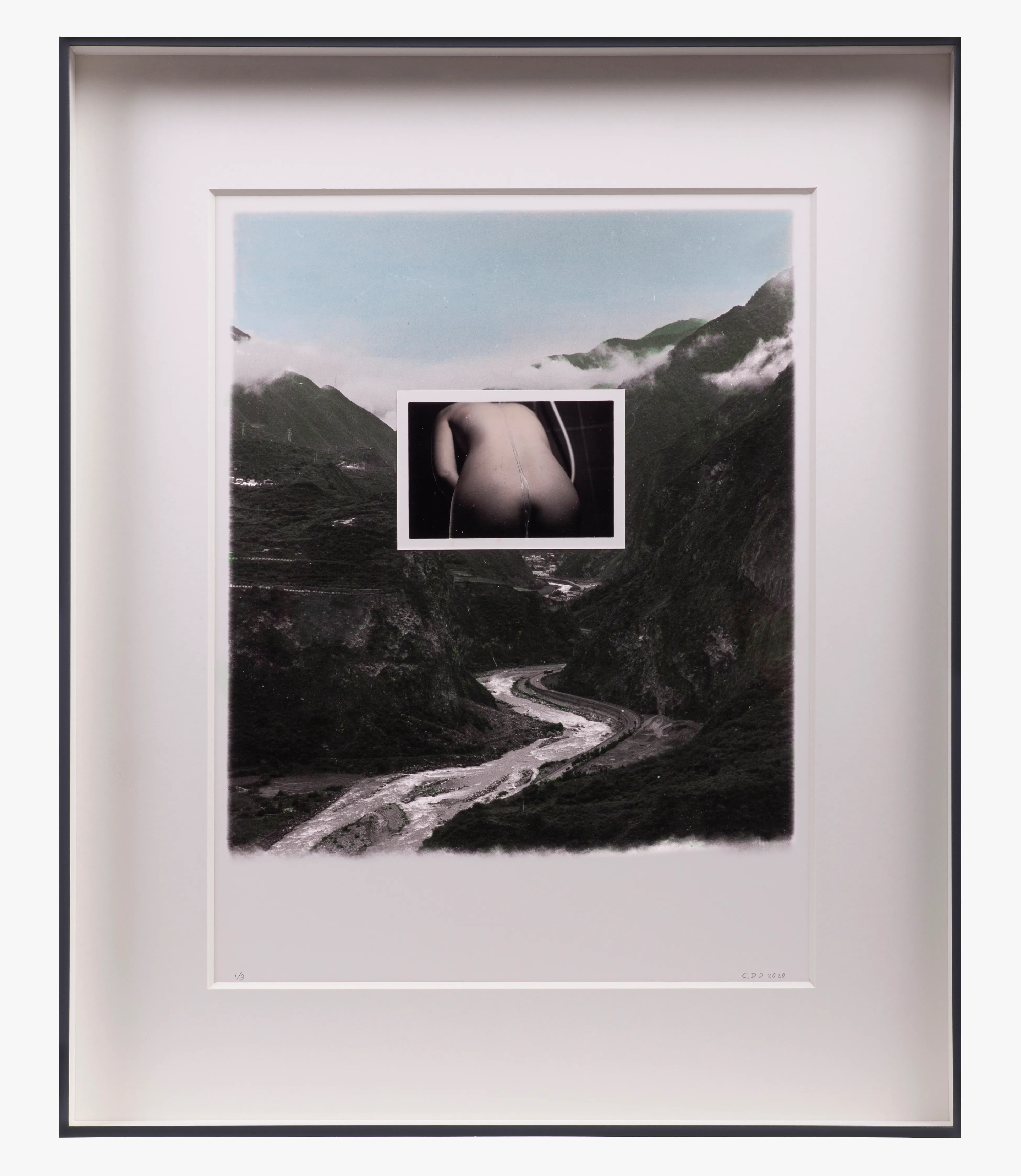 Framed photograph of a mountain landscape with a river and a central inset of a person's back